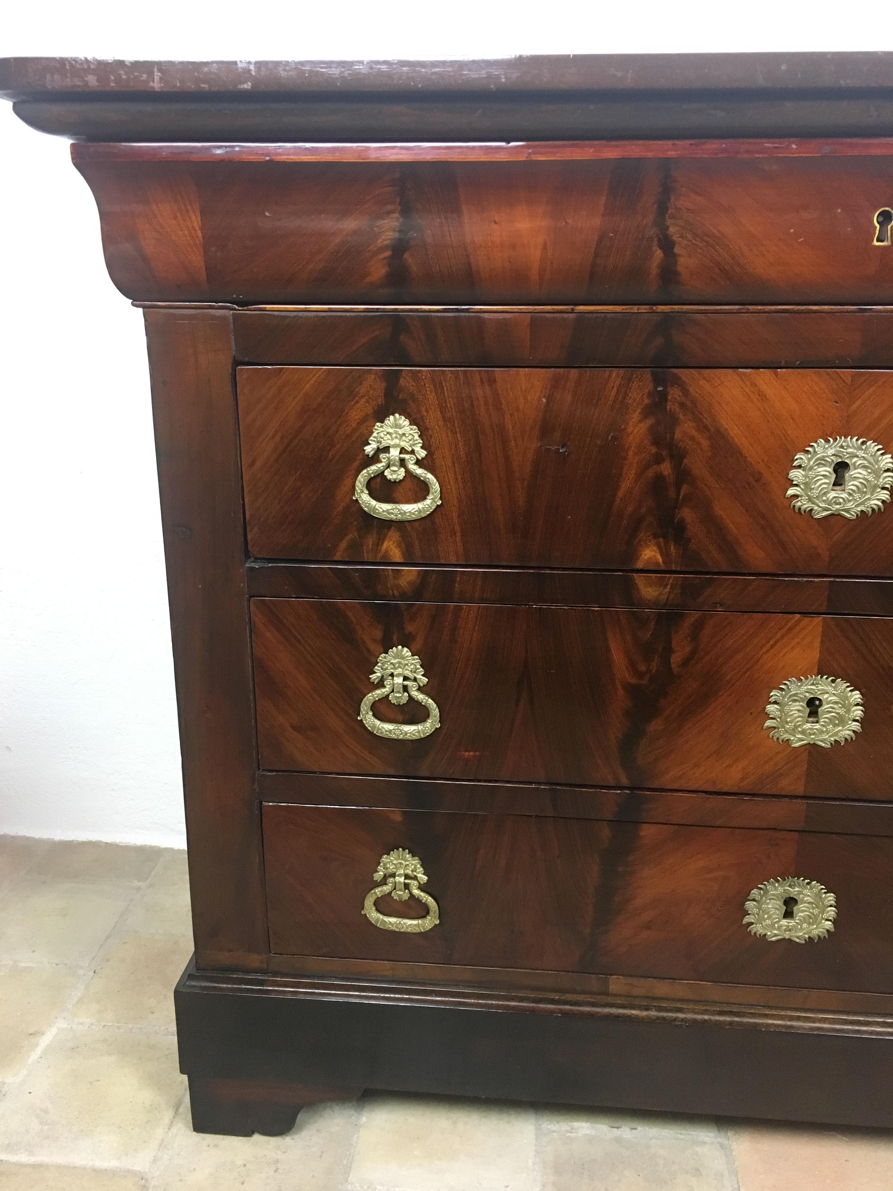 A fine French Louis Philippe period commode made of solid flame mahogany and veneer. Featuring four long fitted drawers with brass keyholes for all of them. 

This piece has an original flame mahogany top, very rare, instead of the more common