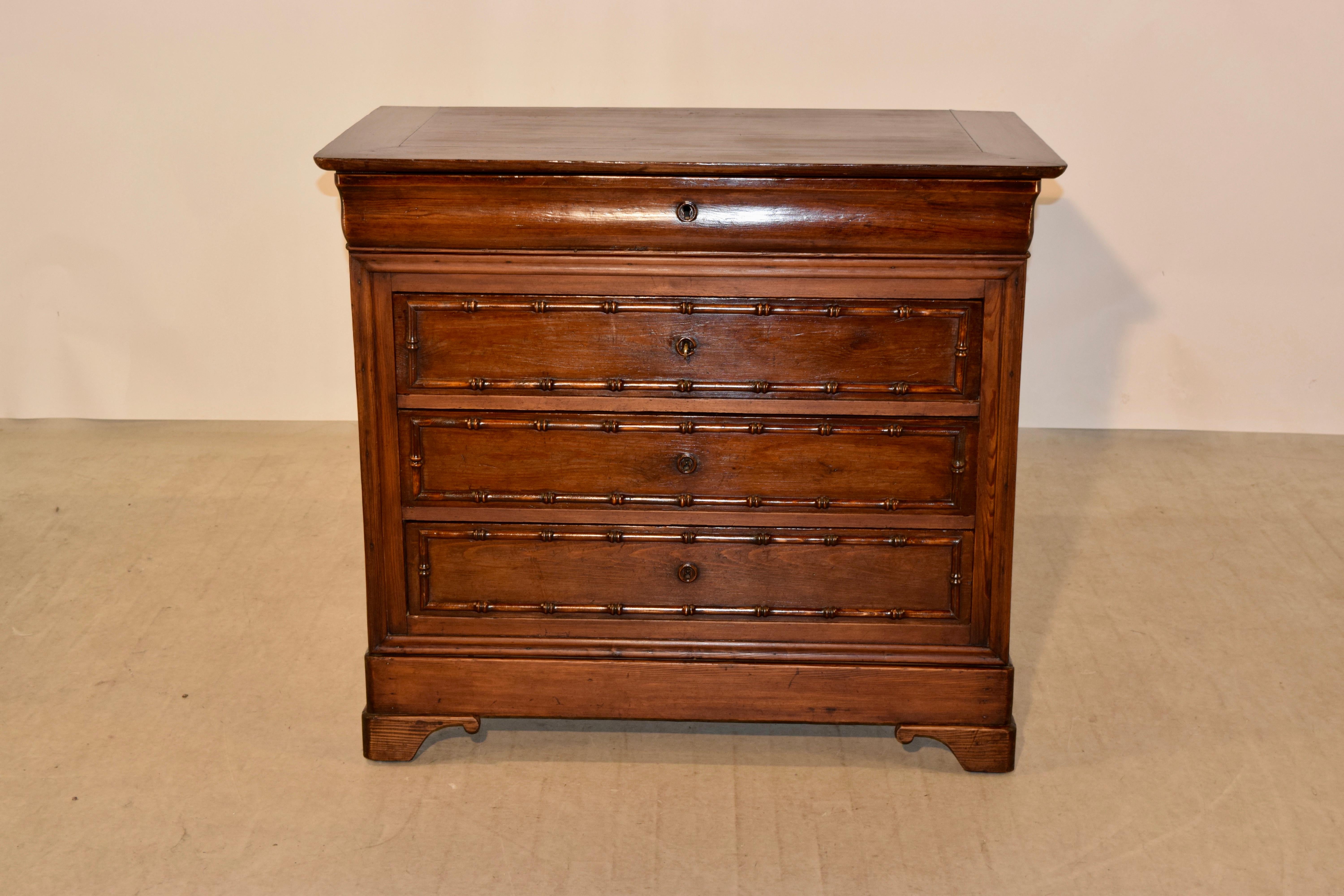 19th century French commode made from pitch pine and cherry. It has a banded top following down to simple sides, which have shrinkage from age. The case has four drawers, the top one hidden in the molded apron and three others below. The lower