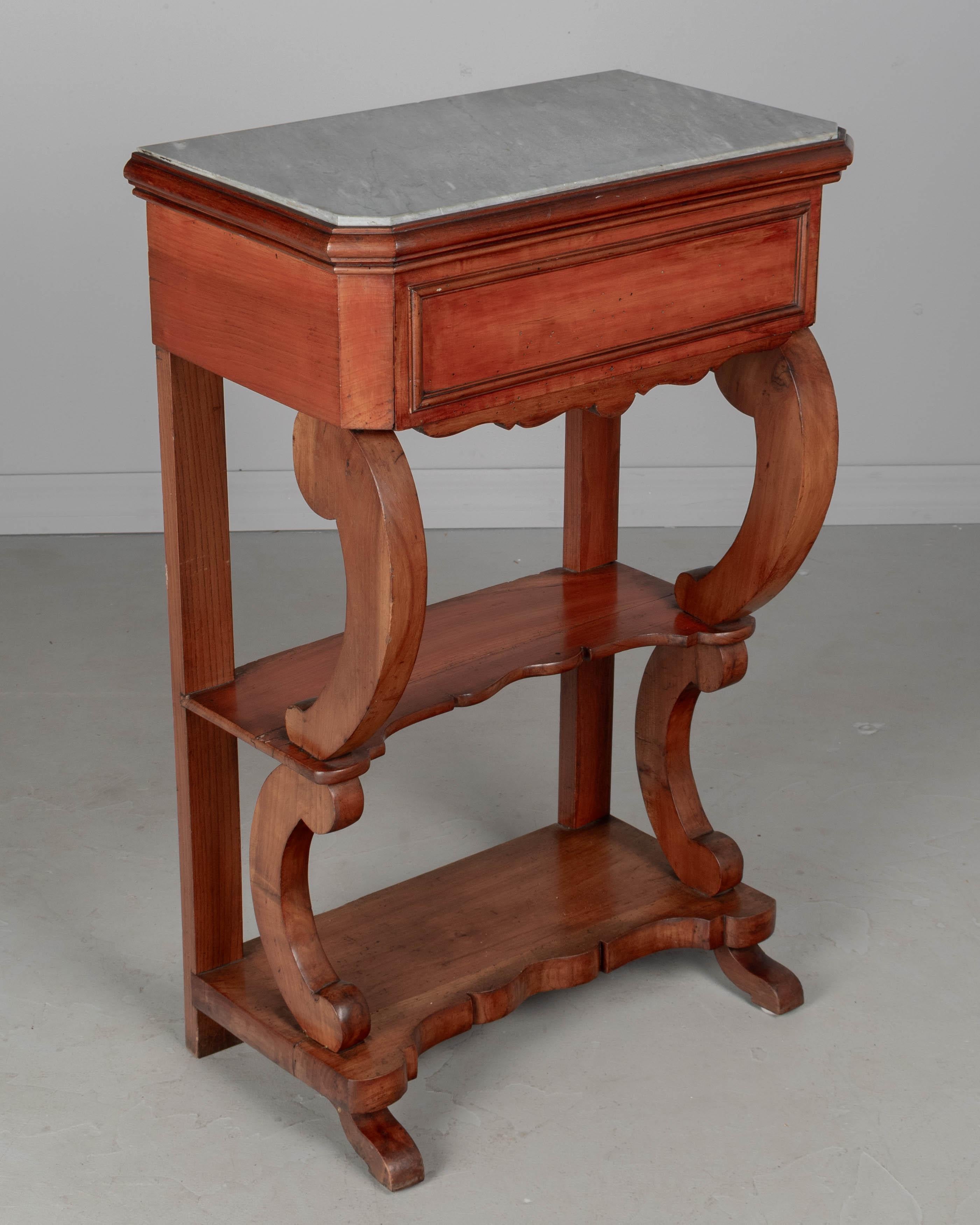 A 19th century Louis Philippe style console table made of solid cherry wood with a dovetailed drawer below a Blue Turquin marble top. Shaped shelf and base with curved supports. All original. Circa 1880-1900.
Dimensions: 21.75