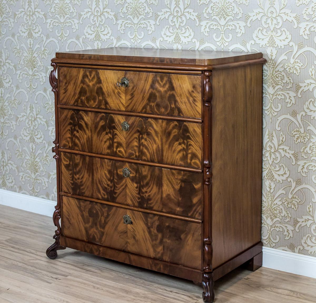 We present you this piece of furniture in mahogany veneer, circa the Q3 of the 19th century.
The corpus has four drawers and cut corners with layered moldings made of pediments with volutes overlapping the front legs, whose S-like shape is similar