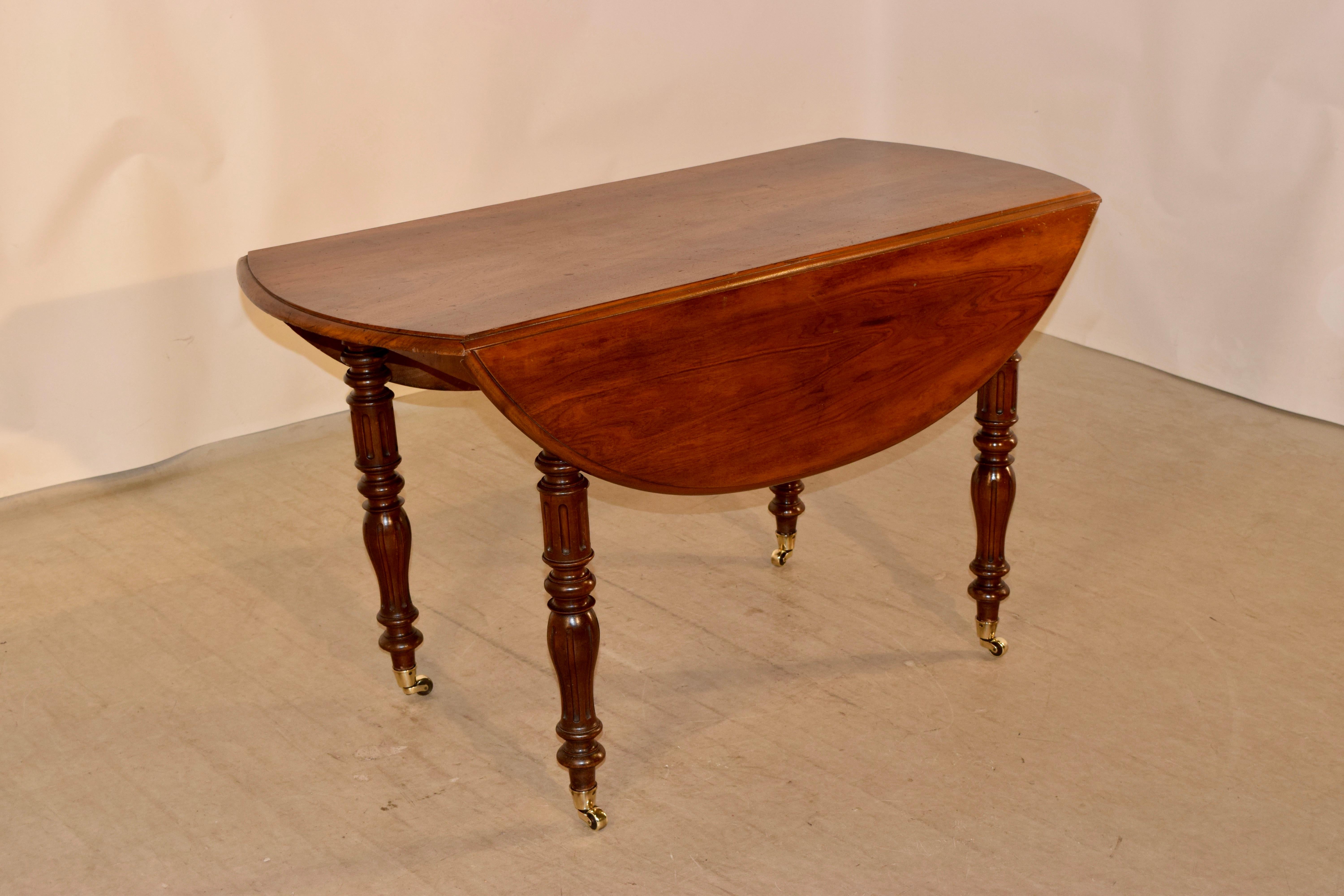 19th century Louis Philippe drop-leaf table in cherry, from France. The top has wonderful graining and beveled edges. The top opens to measure 49.88 x 44.The top is over a simple apron and raised on hand-turned and fluted legs on brass casters.