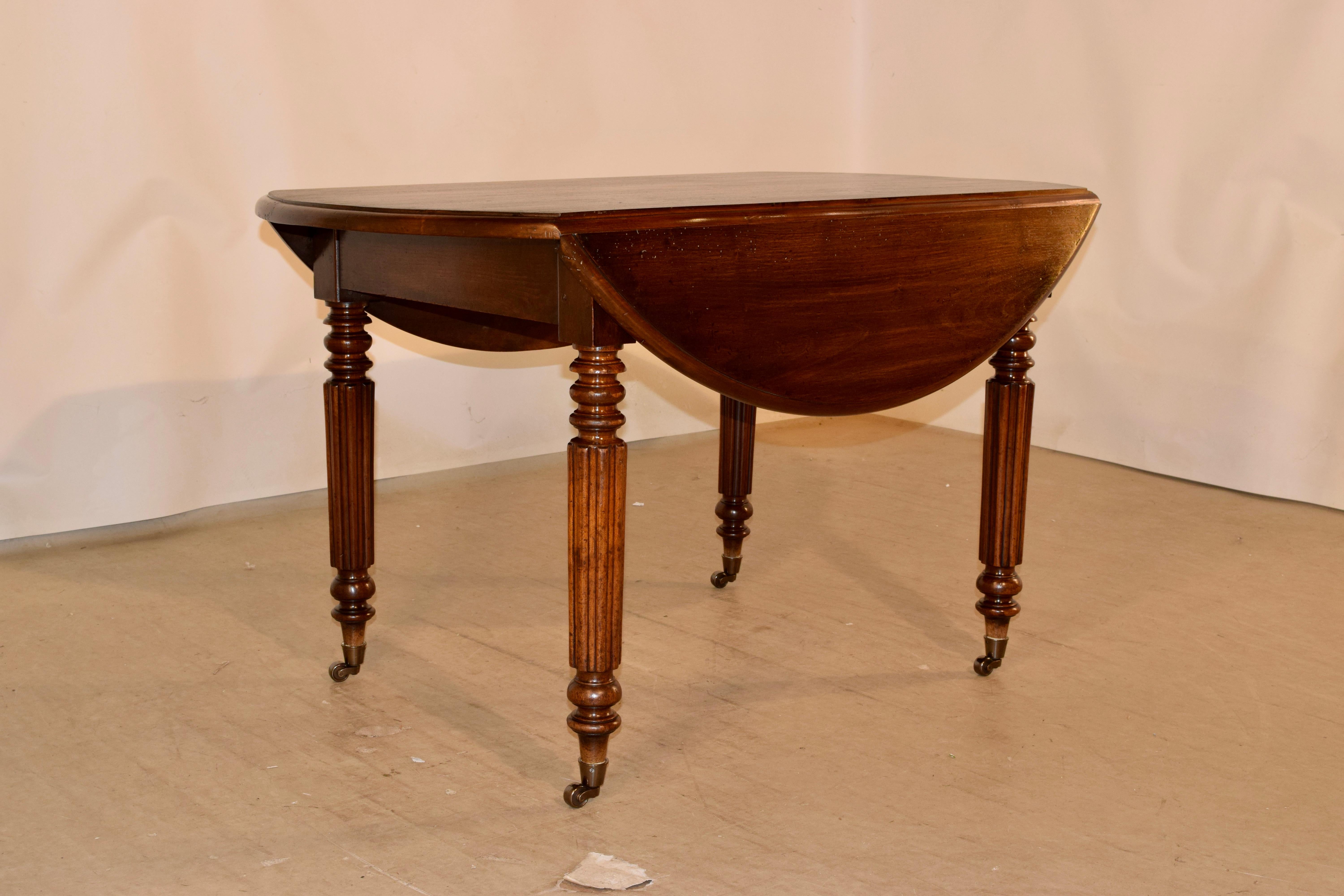 19th century Louis Philippe drop-leaf table in walnut, from France. The top has wonderful graining and beveled edges. The top opens to measure 47.25 x 46.5. The top is over a simple apron and raised on hand-turned and reeded legs on brass casters.