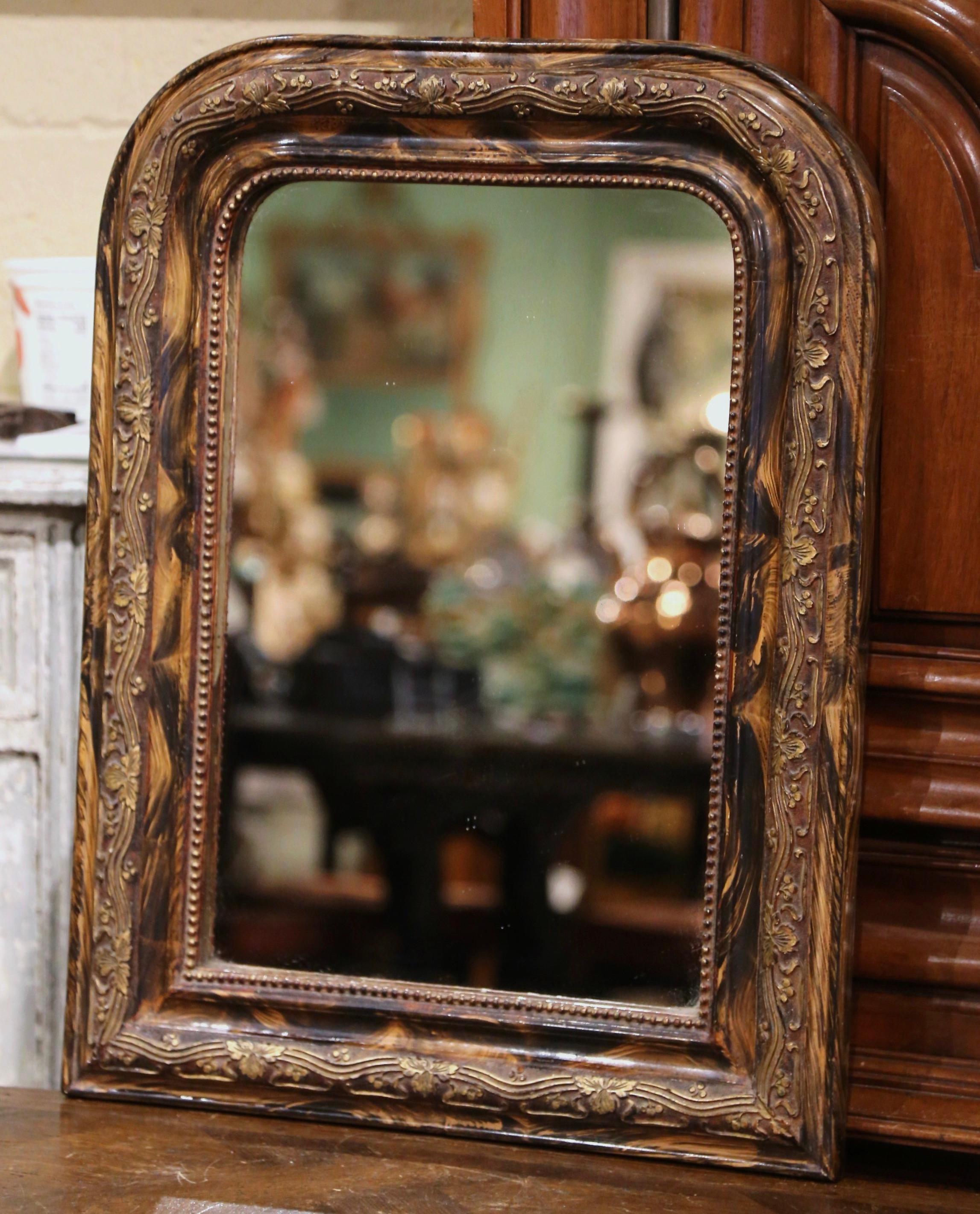 Cet élégant miroir mural ancien a été fabriqué en France, vers 1880. Le cadre aux angles arrondis est décoré de motifs de vigne dorés en haut-relief entre des décors peints en faux bois de ronce ; il est également orné d'un décor de perles sur le