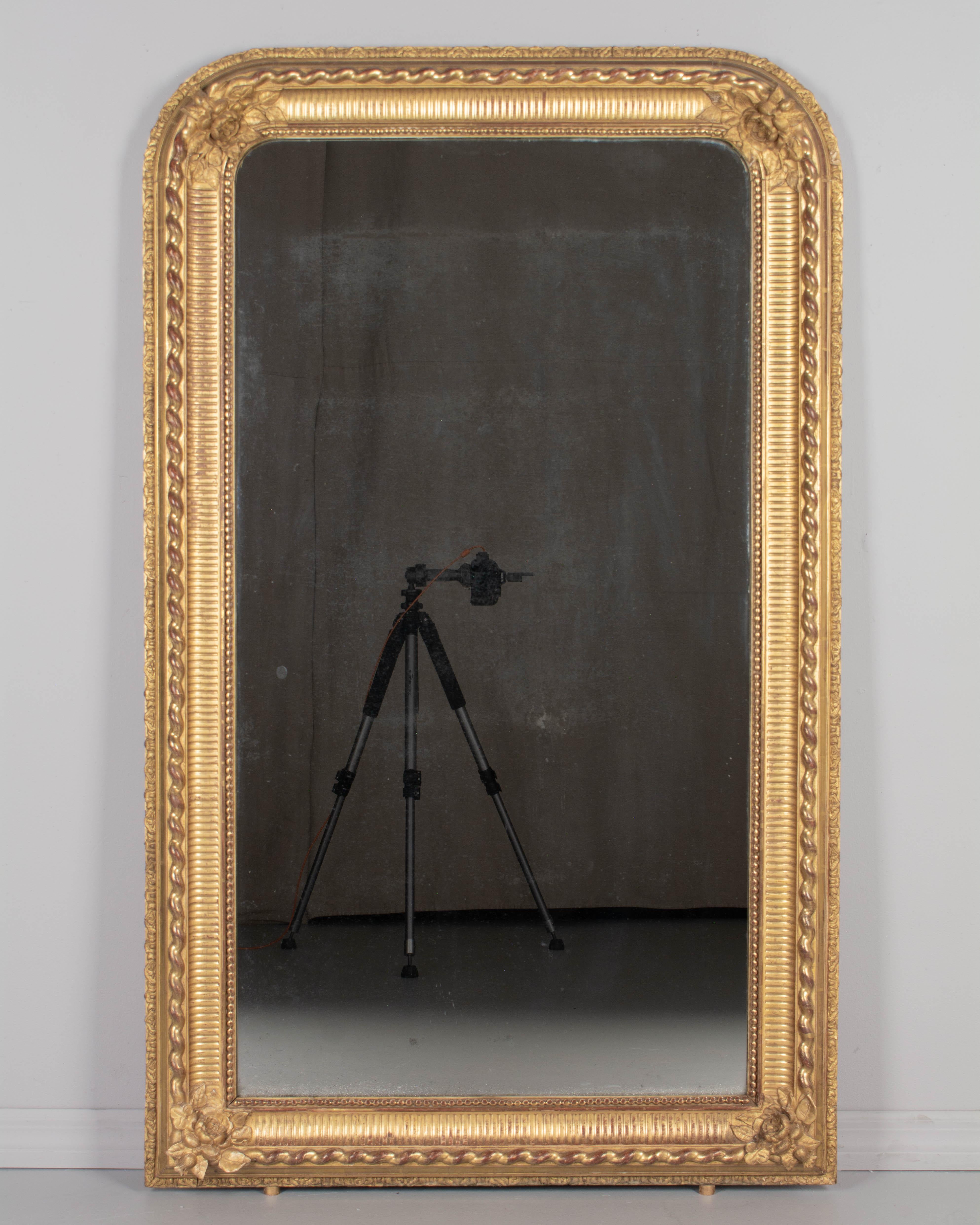 Specchio in legno dorato francese Louis Philippe del XIX secolo con fiori in gesso agli angoli. Cornice splendidamente dettagliata con nervature, corda ondulata, bordo interno di perline e bordo esterno decorativo. Forma e qualità eccezionali. La