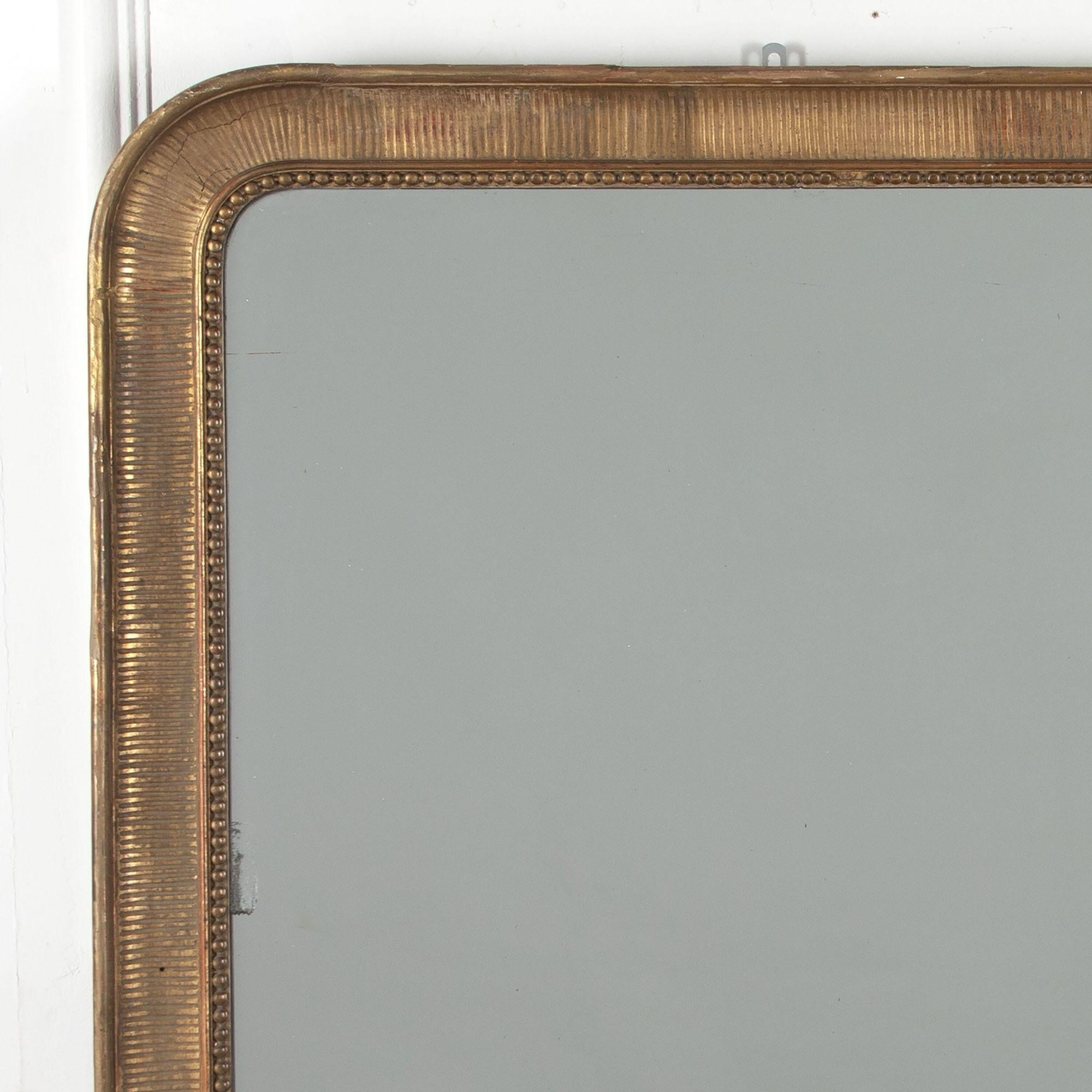 19th century tall gold gilt Louis Philippe mirror.
With elegantly carved bead surround and ribbed decorative frame and original mirror plate.
With statement proportions, circa 1860.