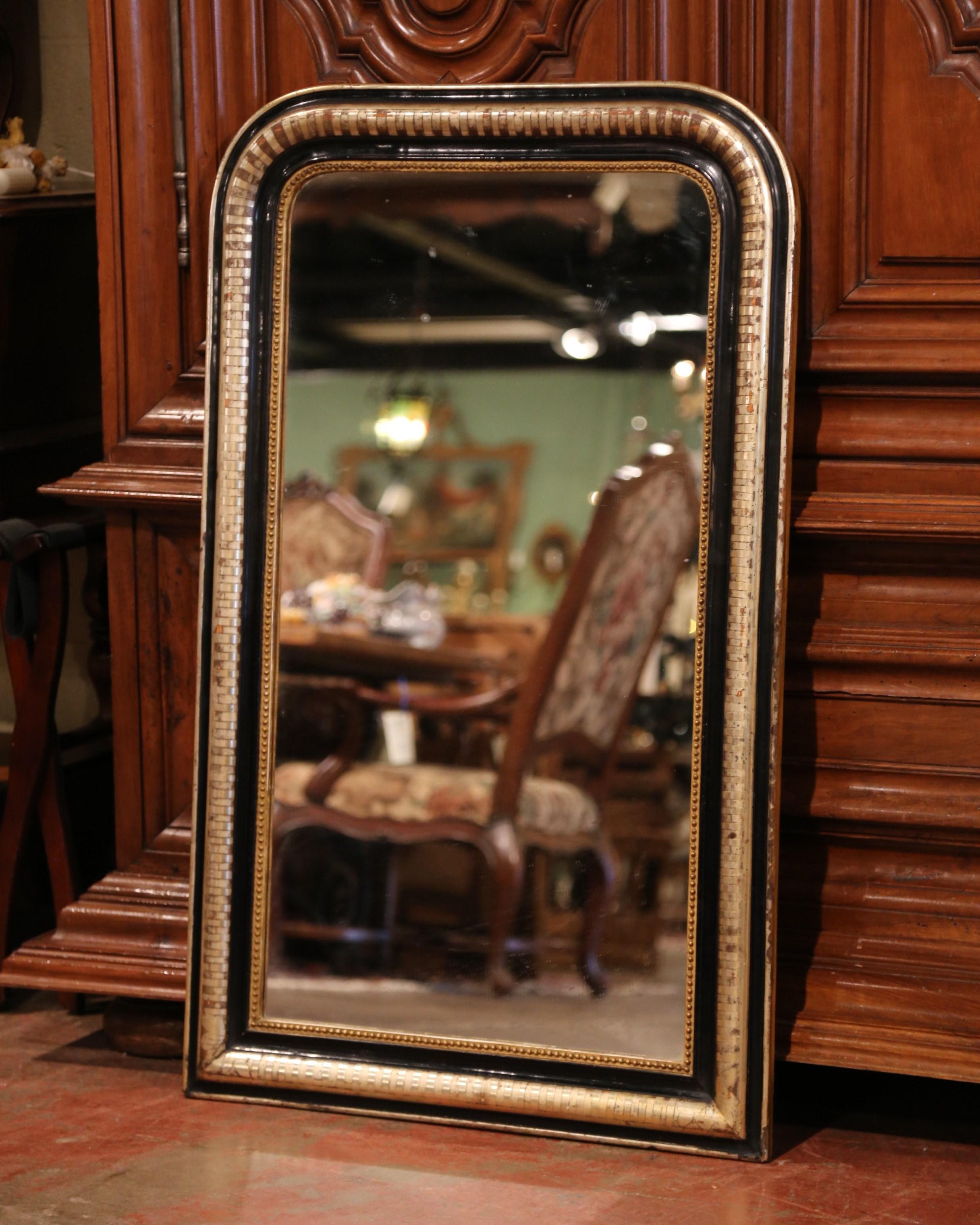This elegant antique two-tone gold leaf and black lacquered mirror was crafted in France, circa 1860. The large frame is decorated with engraved stripe motif, and is further embellished with beads and gilt all around. The wall hanging piece is in