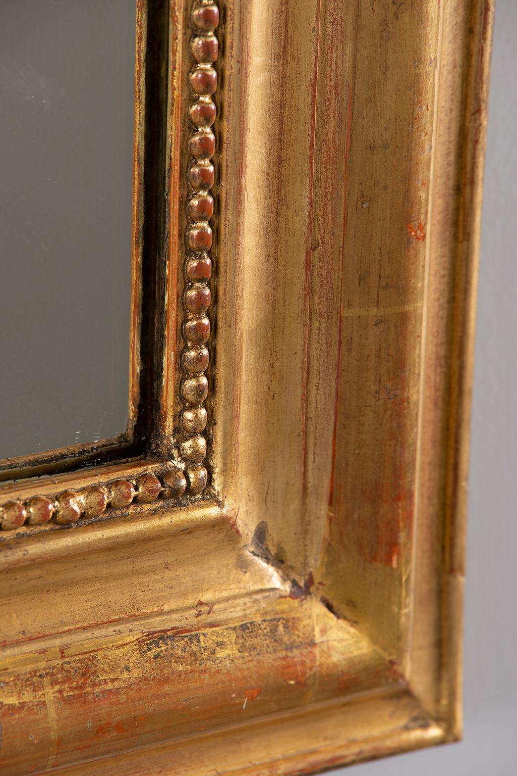 Louis Philippe wide wood frame mirror with gilt finish. Subtle decorative elements include a beaded inner border and etched floral spray borders on the top, sides and base. Actual mirror size, without frame, is 23.5