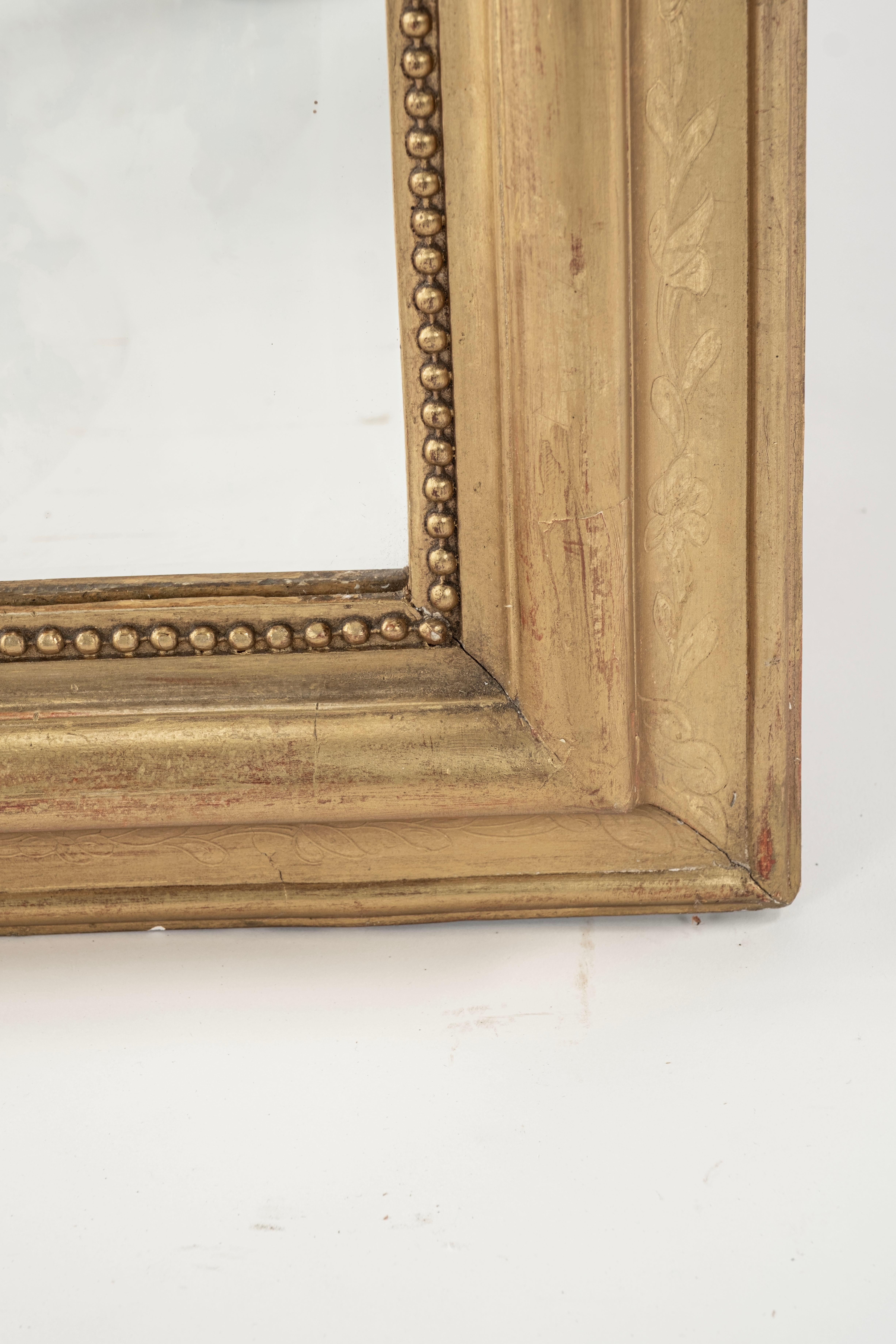  A 19th century French Louis Philippe overmantle / wall mirror. The original gilding to this impressive mirror is in superb condition with just a little historical surface wear. Revealed beneath is the original reddish bole base coat creating a