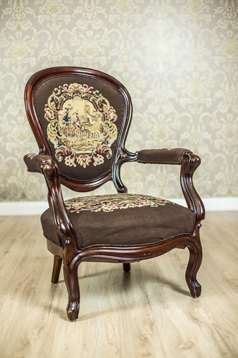 We present you this armchair, circa 19th century, made of mahogany wood. What is interesting is that it has its seat, backrest, and armrests upholstered softly.
Moreover, these parts are upholstered with a fabric in the Berlin type, depicting a