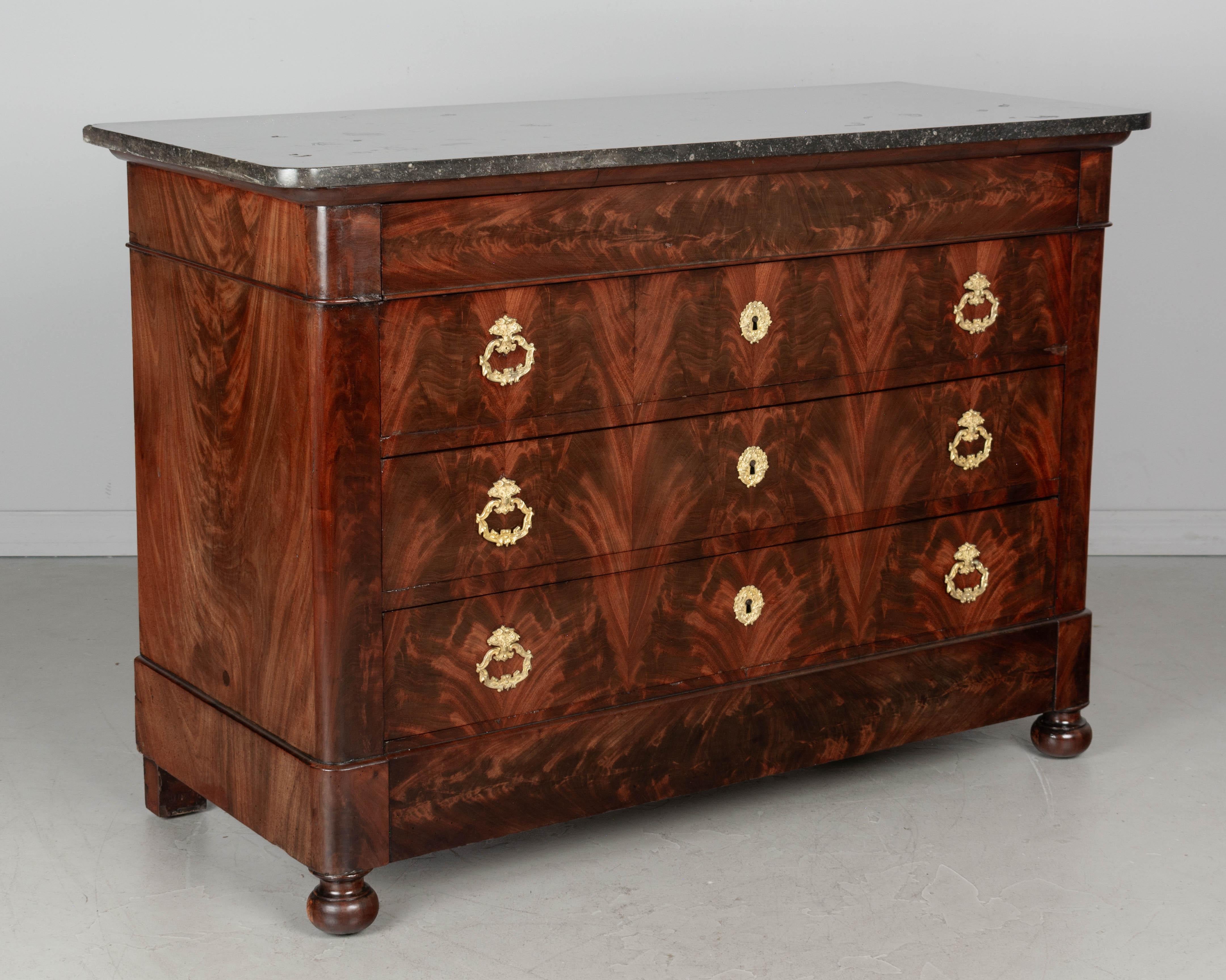 An early 19th century French Louis Philippe mahogany commode, or chest of drawers with marble top. Fine craftsmanship with book-matched flame mahogany veneer retaining a nice luster. Oak as a secondary wood. Four dovetailed drawers, with clean