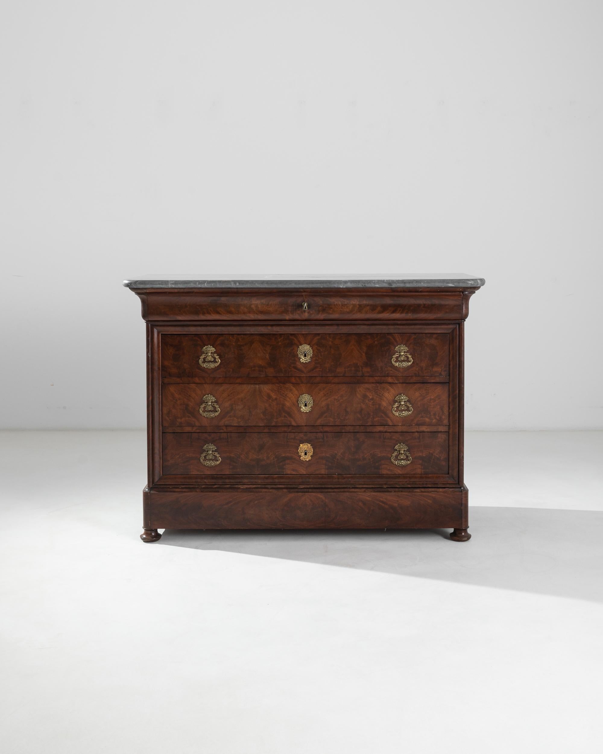 This antique wooden chest of drawers epitomizes the sober elegance of Louis Philippe furniture. Built in France in the 19th century, the straight lines of the simple, upright cabinet are softened by the gentle doucine curve of the uppermost drawer