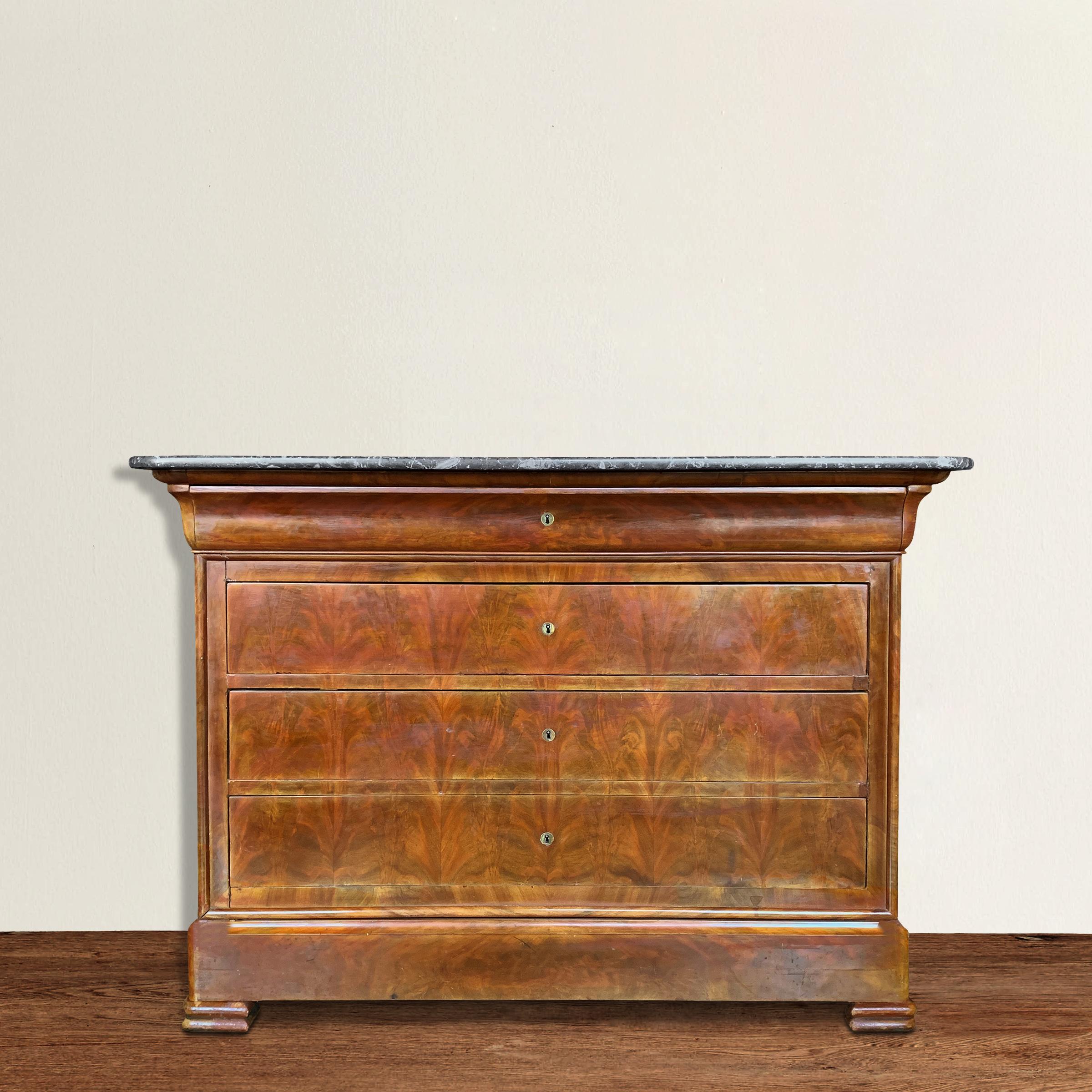 A striking early 19th century French Louis Philippe black marble-topped mahogany-stained walnut chest with four visible drawers with working locks, and another drawer hidden in the trim at the bottom. Original key included. The perfect nightstand or