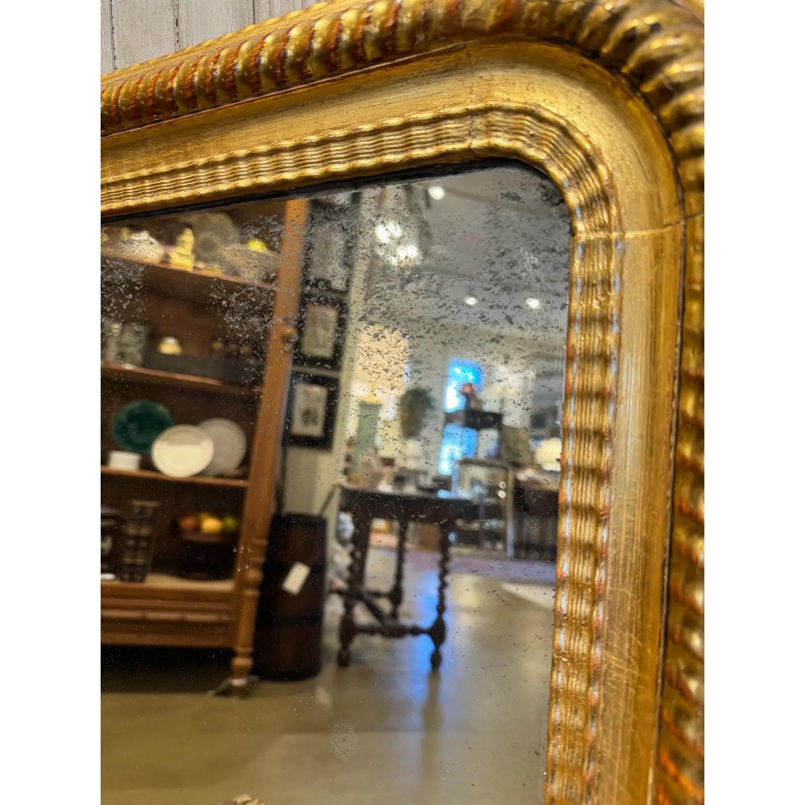 This exquisite Antique Louis Philippe Mirror, adorned with a gilded finish, effortlessly brings timeless charm to any space. Its ornate banded detailing and classic design make it a captivating centerpiece, reflecting both style and history in a