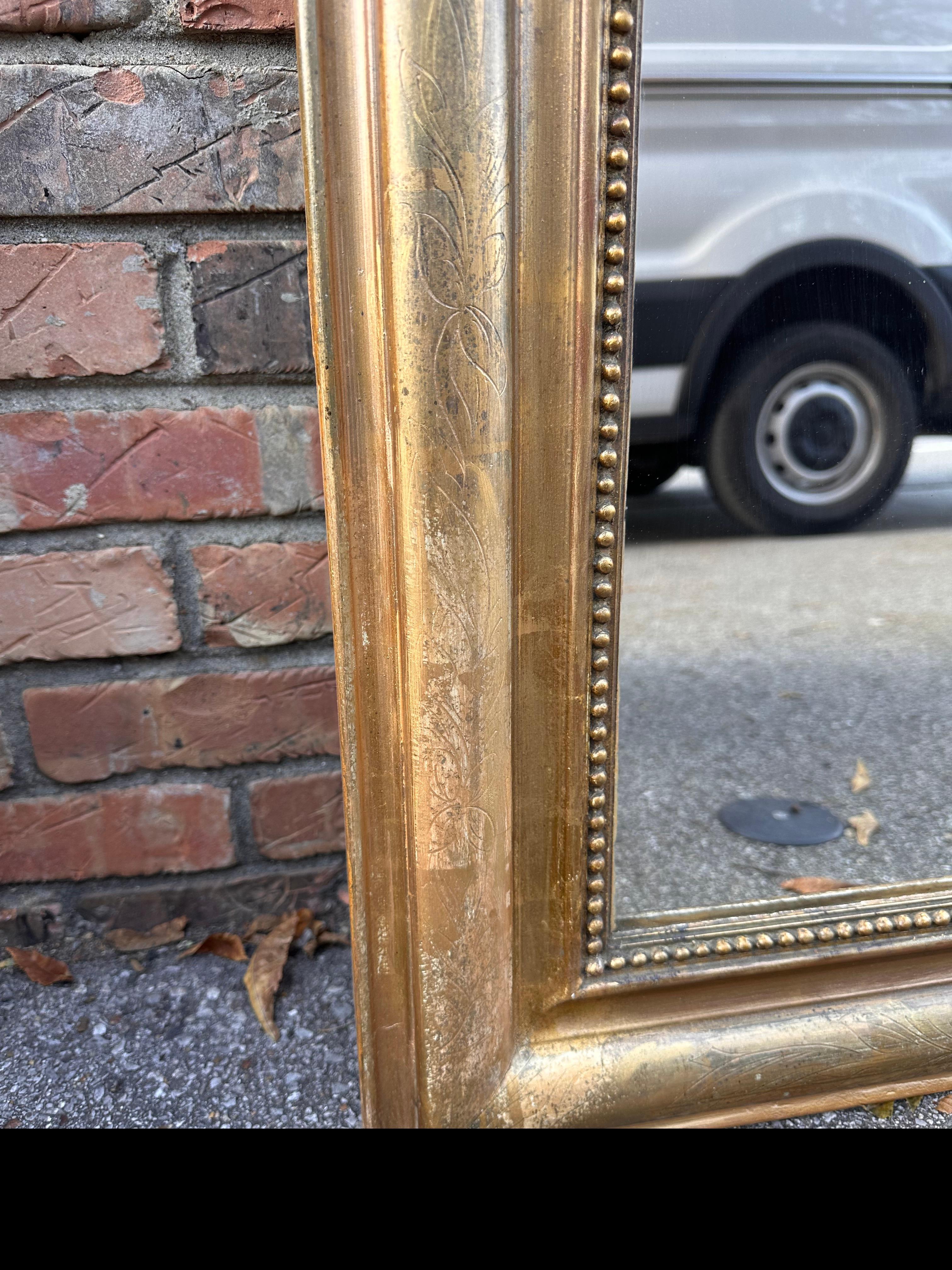 Dies ist ein schöner Louis Philippe-Spiegel aus dem 19. Jahrhundert. Dieses Stück ist in ausgezeichnetem Zustand, ohne Fehlstellen in der inneren Perlenbordüre. Die äußere Umrandung ist mit handgeschnitzten Blumendetails versehen, und das Gold