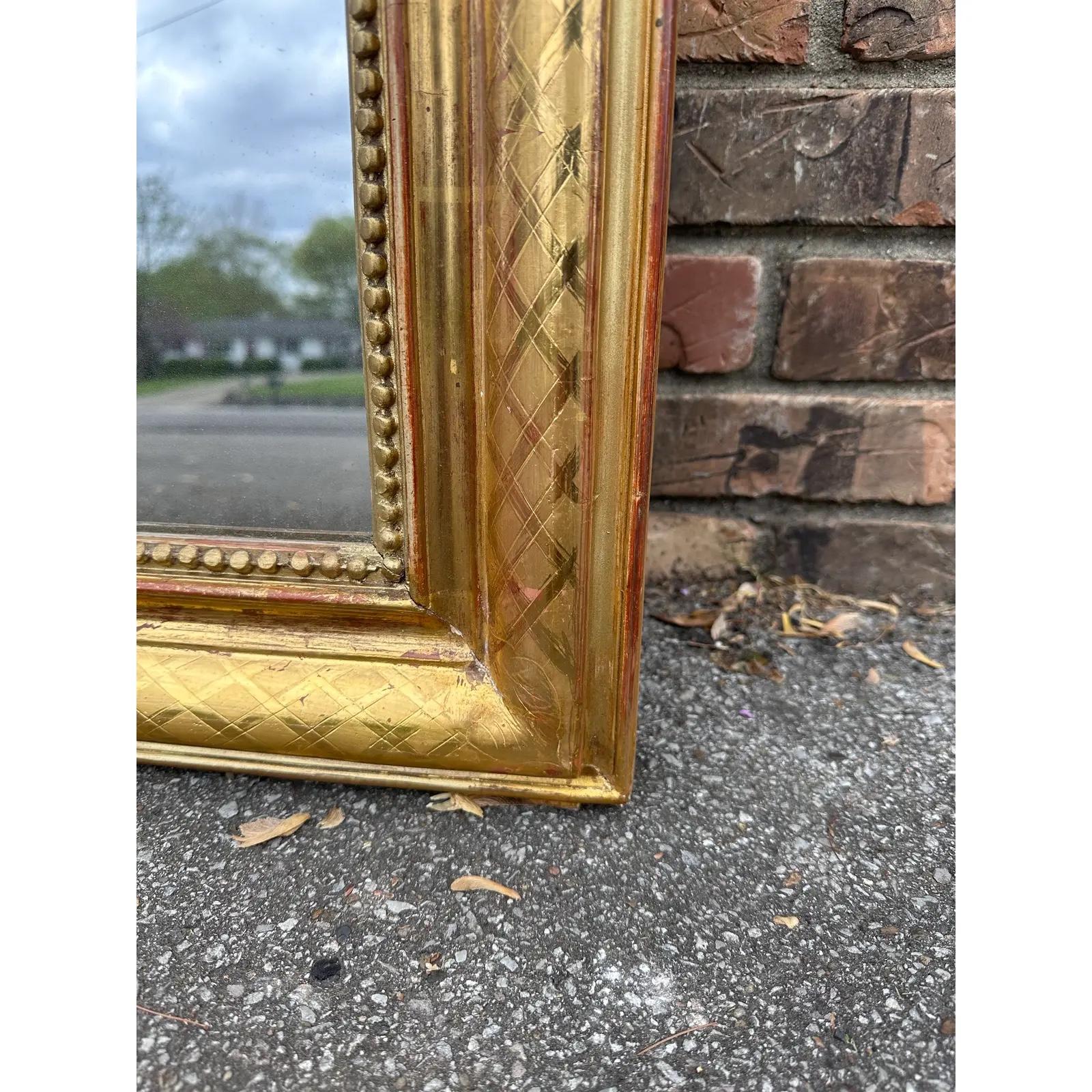 Cet exquis miroir Louis Philippe antique, orné d'une finition dorée, apporte sans effort un charme intemporel à n'importe quel espace. Ses détails ornés et son design classique en font une pièce maîtresse captivante, reflétant à la fois le style et