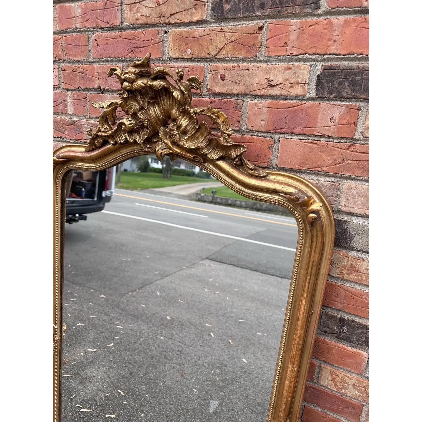 This 19th Century French mirror is top of its class! With its stunning gilded adornments such as its hand carved edging, ornate cartouche, and oversized silhouette, this mirror is bound to make a grand impression in any space. It has all of its