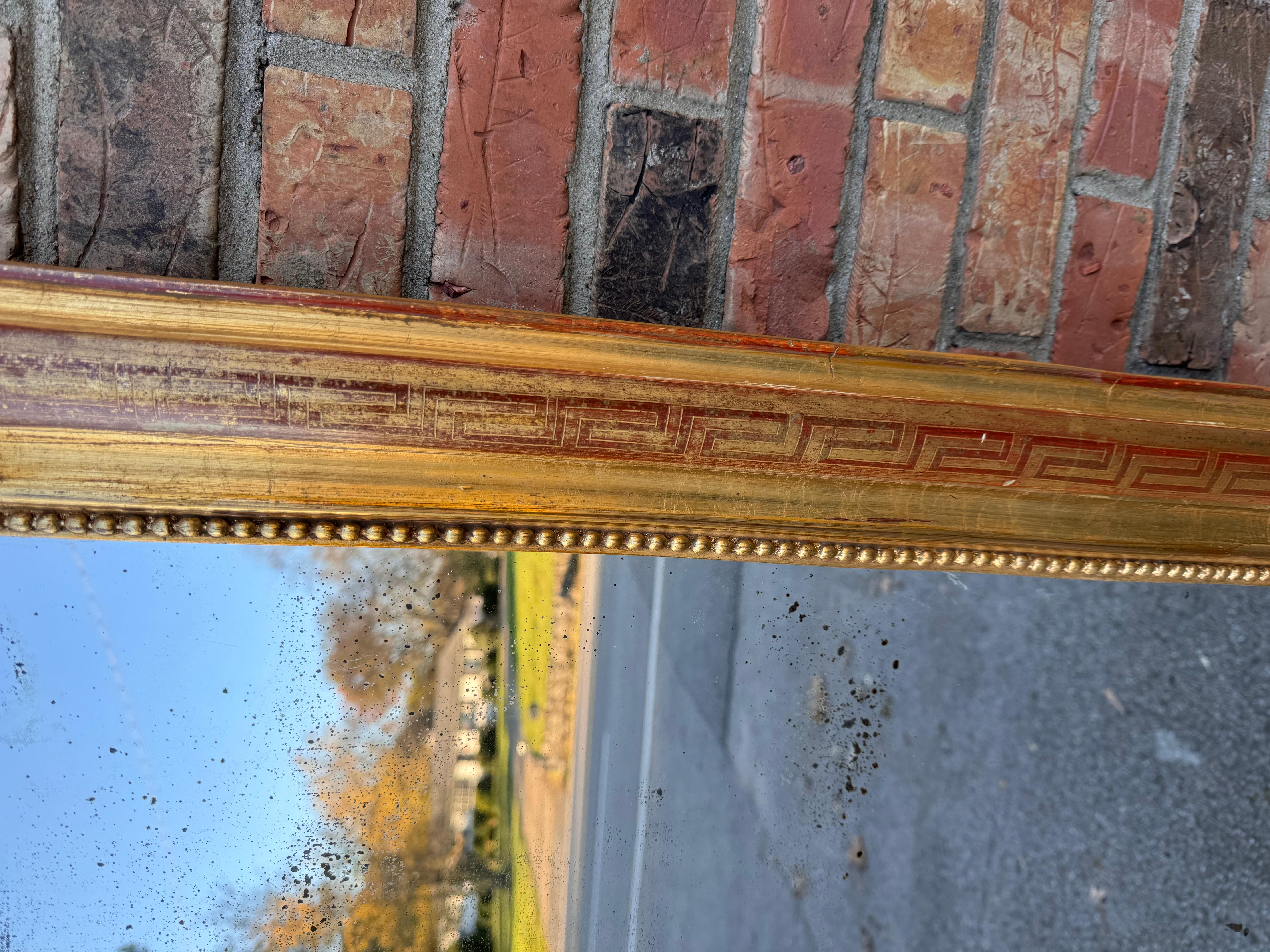 This is a gorgeous antique French mirror! This piece is in excellent condition, with all borders in tact- no missing pieces. The inner border is beaded, while the outer border is a beautiful hand carved with a Greek Key pattern running across the