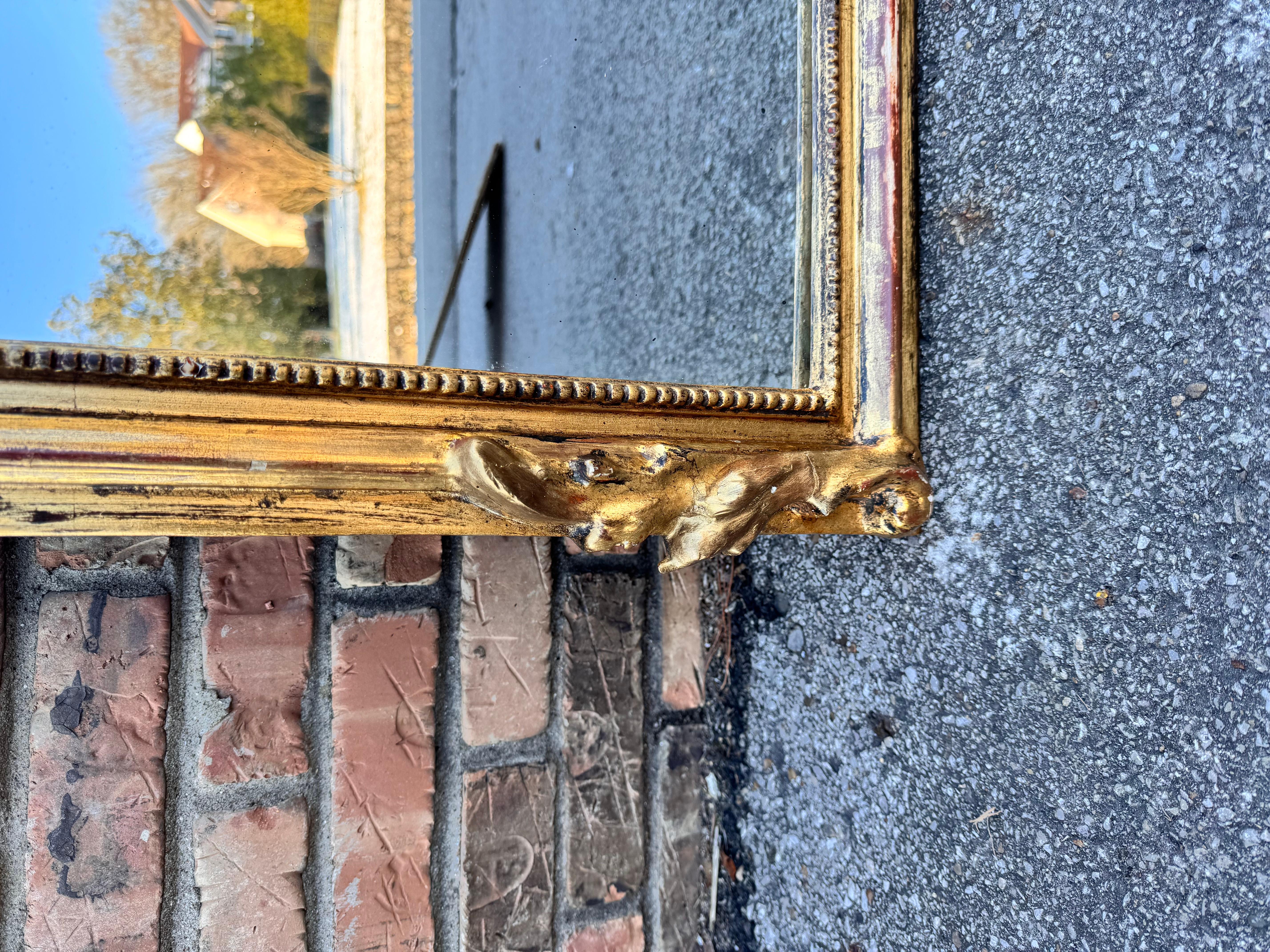 Ce miroir français du 19e siècle est le meilleur de sa catégorie ! Avec ses étonnants ornements dorés tels que sa bordure sculptée à la main, son cartouche orné et sa silhouette surdimensionnée, ce miroir ne manquera pas de faire grande impression