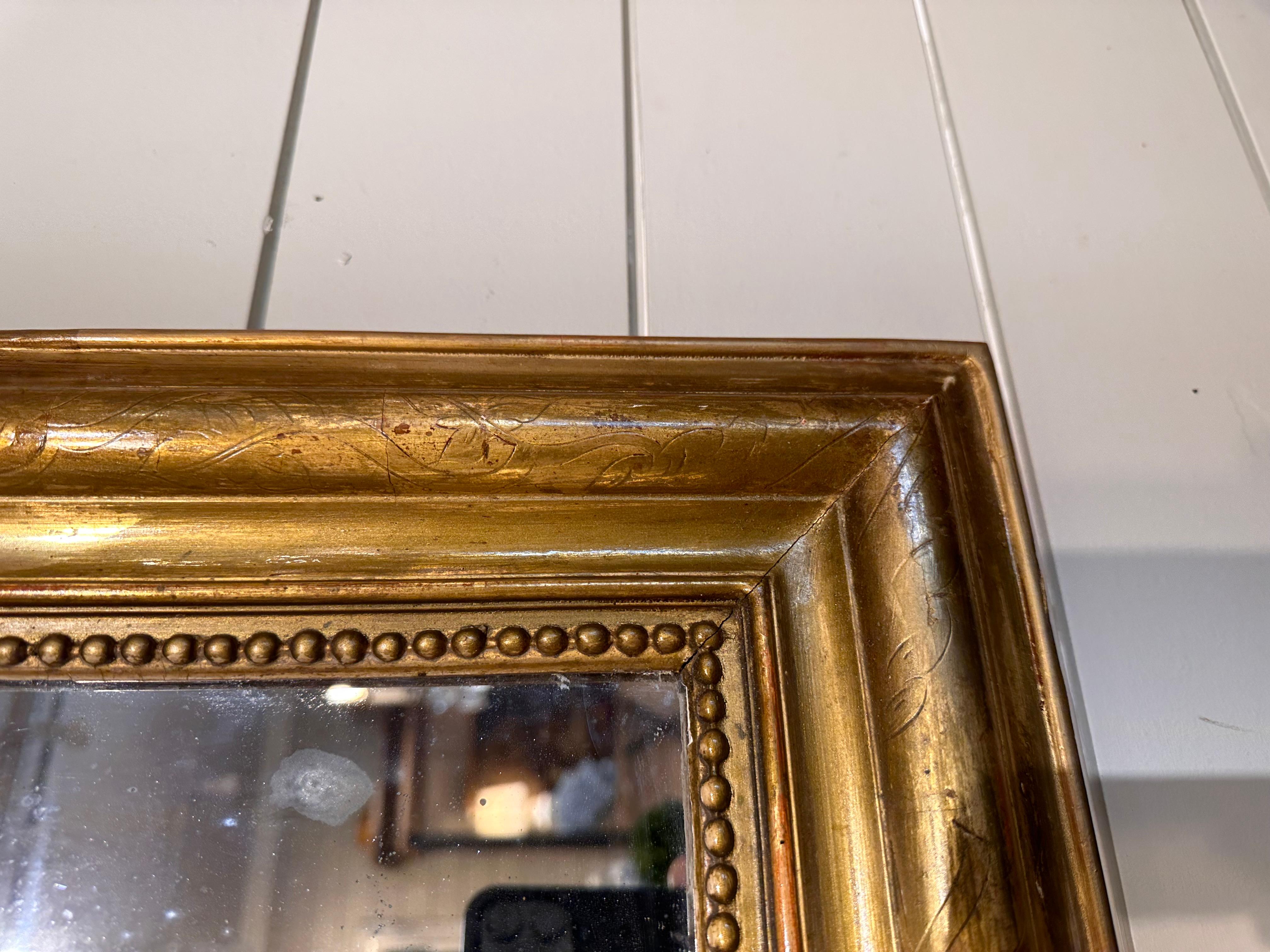 This is a beautiful 19th century Louis Philippe Mirror. This piece is in excellent condition with no missing pieces in the beaded inner border. The exterior border has hand carved floral detailing on it, an the gold is beginning to fade away in