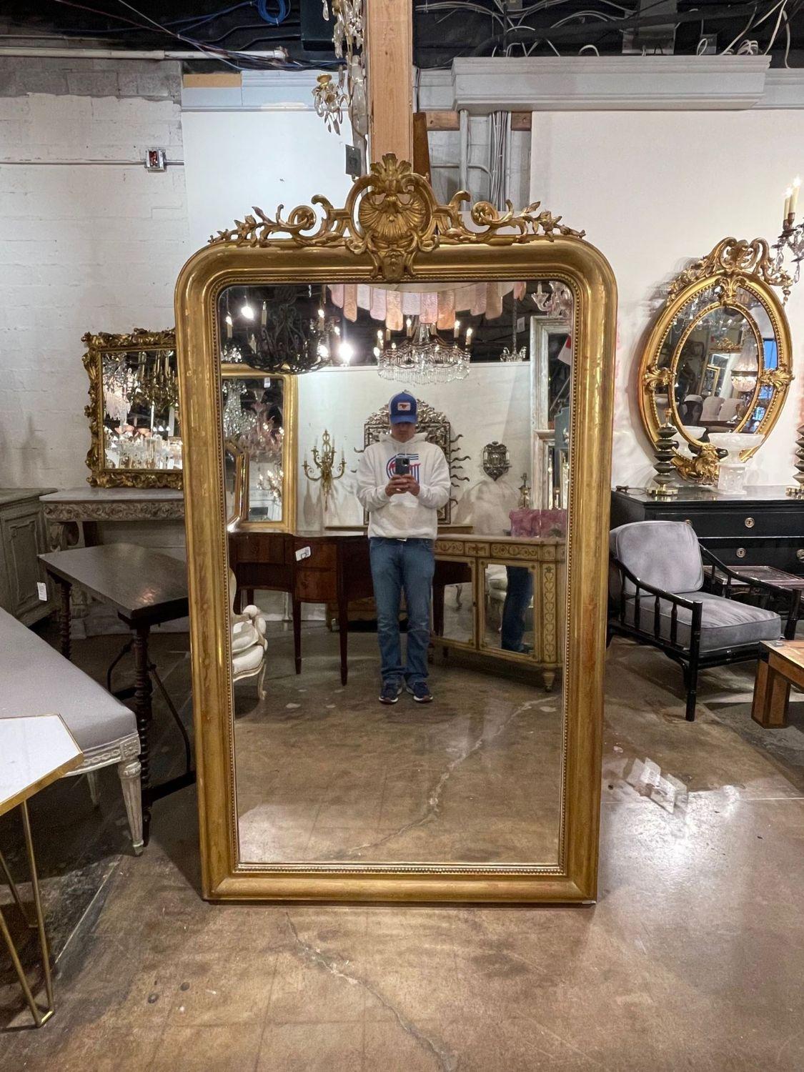 Elegant large scale 19th century gold gilt Louis Philippe mirror. This piece has a beautiful decorative crest at the top along with a floral pattern and beaded inner border. Very impressive!