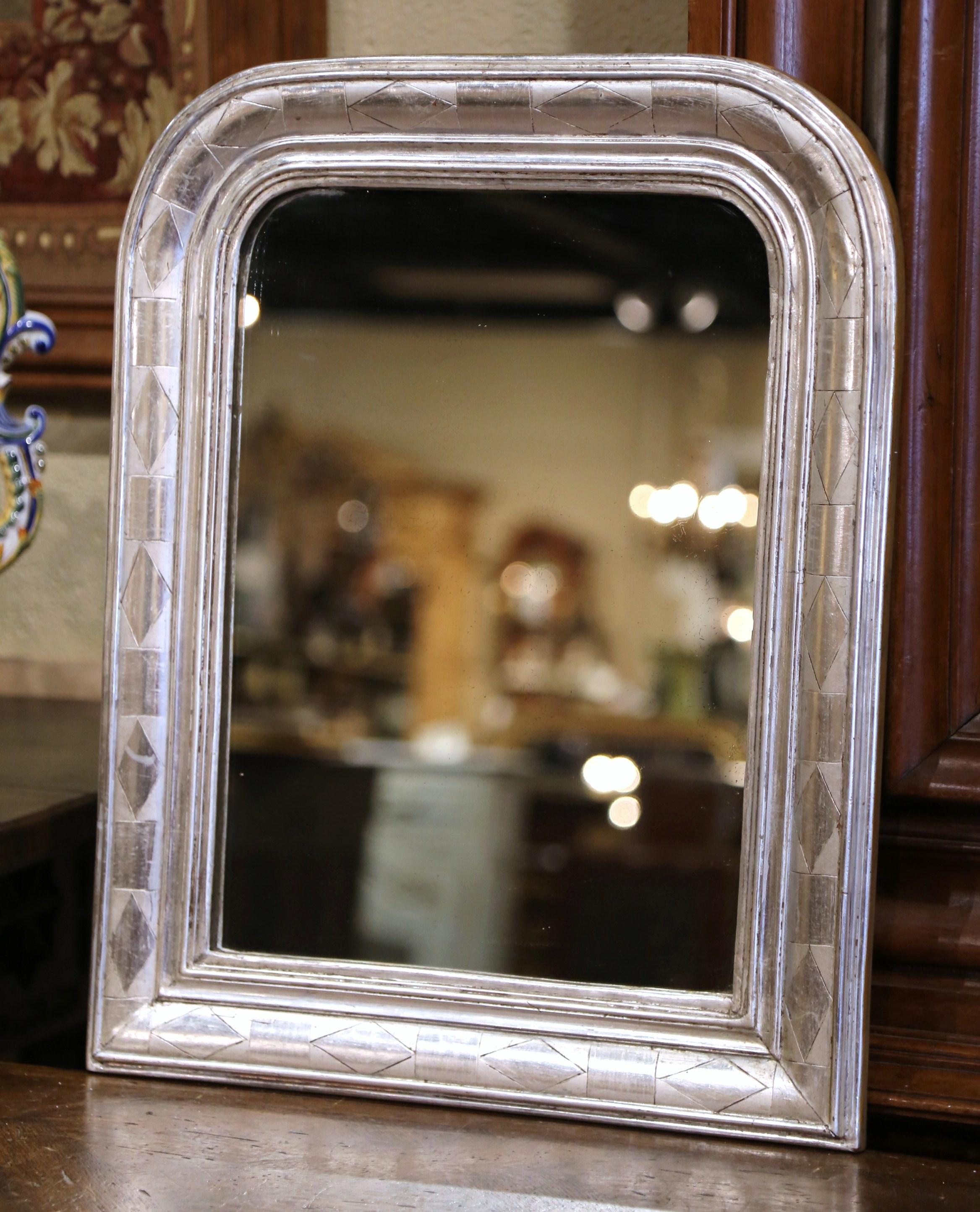 Crafted in the Burgundy region of France, circa 1870, the petite antique mirror has traditional, timeless lines with rounded corners. The elegant frame is decorated with a luxurious silver leaf finish, further embellished with an engraved two-tone