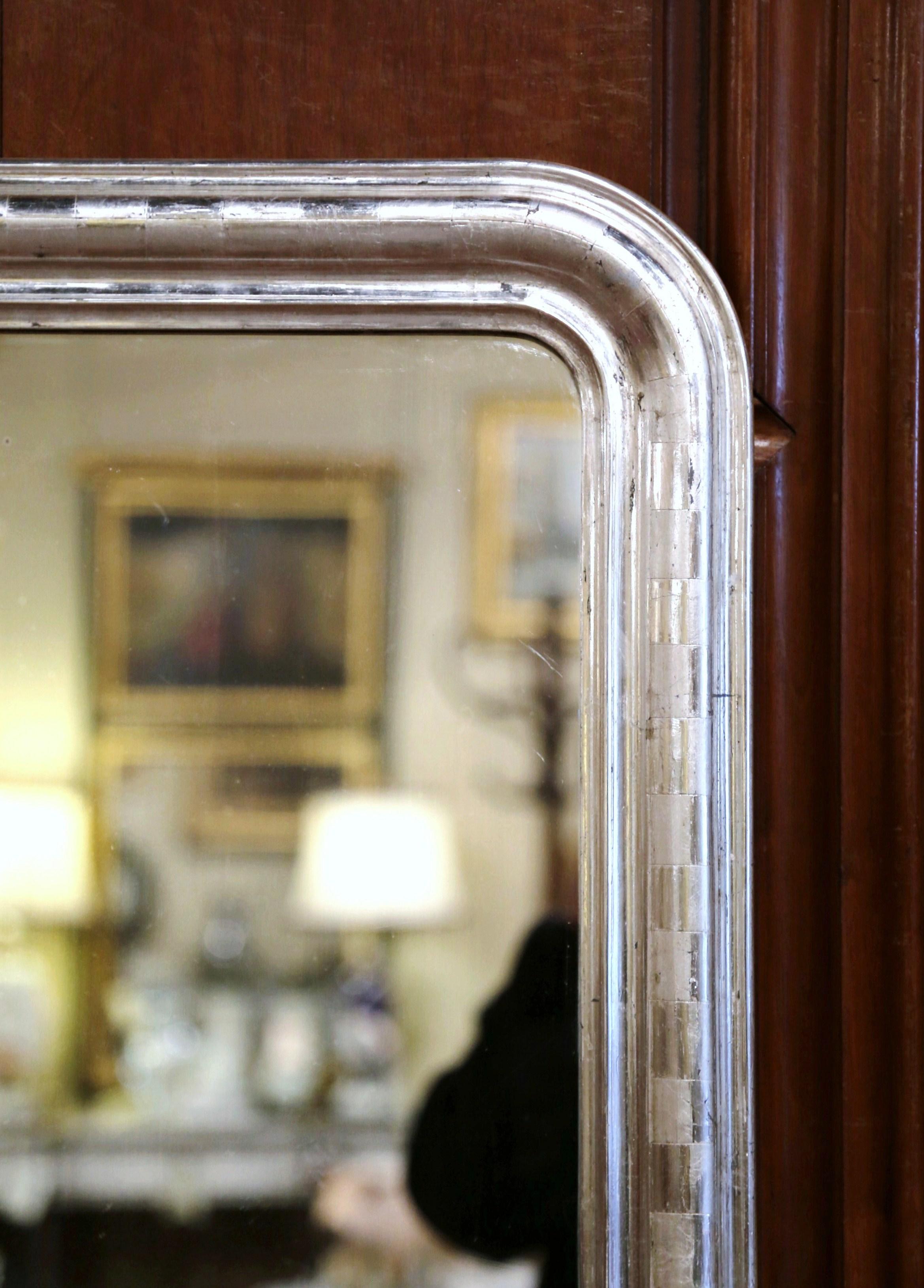 Crafted in the burgundy region of France, circa 1870, the antique mirror has traditional, timeless lines with rounded corners. The elegant frame is decorated with a luxurious silver leaf finish, which is further embellished with an engraved two-tone