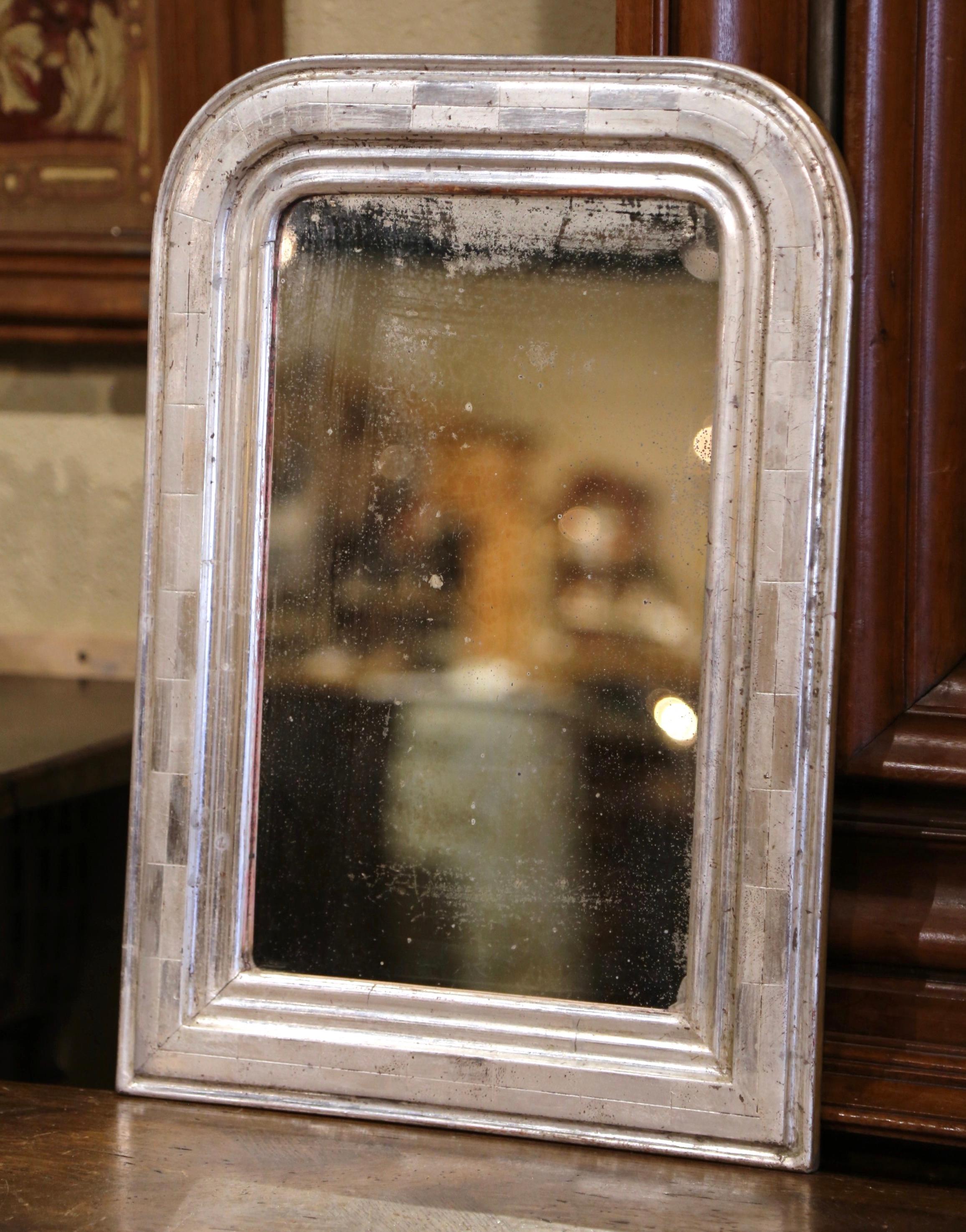Crafted in the Burgundy region of France, circa 1870, the small antique mirror has traditional, timeless lines with rounded corners. The elegant frame is decorated with a luxurious silver leaf finish, further embellished with an engraved two-tone