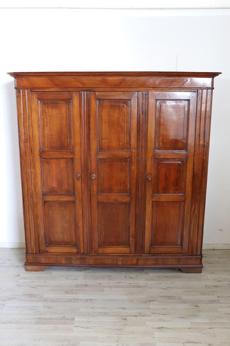 Antique wardrobe in solid walnut wood made in mid 19th century Italian of the period Louis Philippe. This truly spectacular wardrobe is very rare due to its large dimensions equipped with three doors. Very simple and linear. The interior was covered