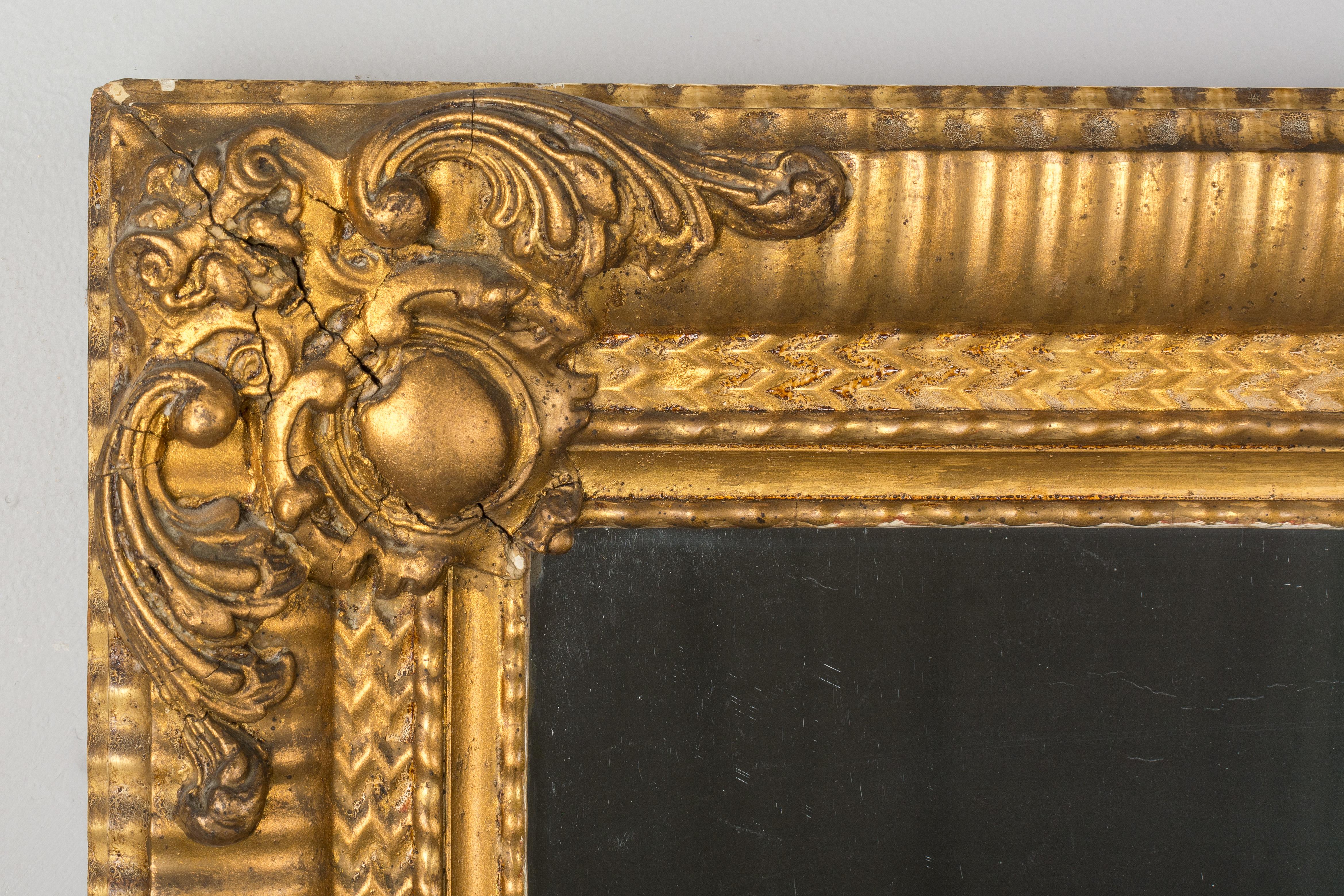 A 19th century French Louis Philippe style giltwood and gesso mirror with three inch wide ribbed frame and corner decorations. Warm gilt finish. Original mirror with old silvering. Minor loss to gilt. Can be hung horizontally or vertically. The