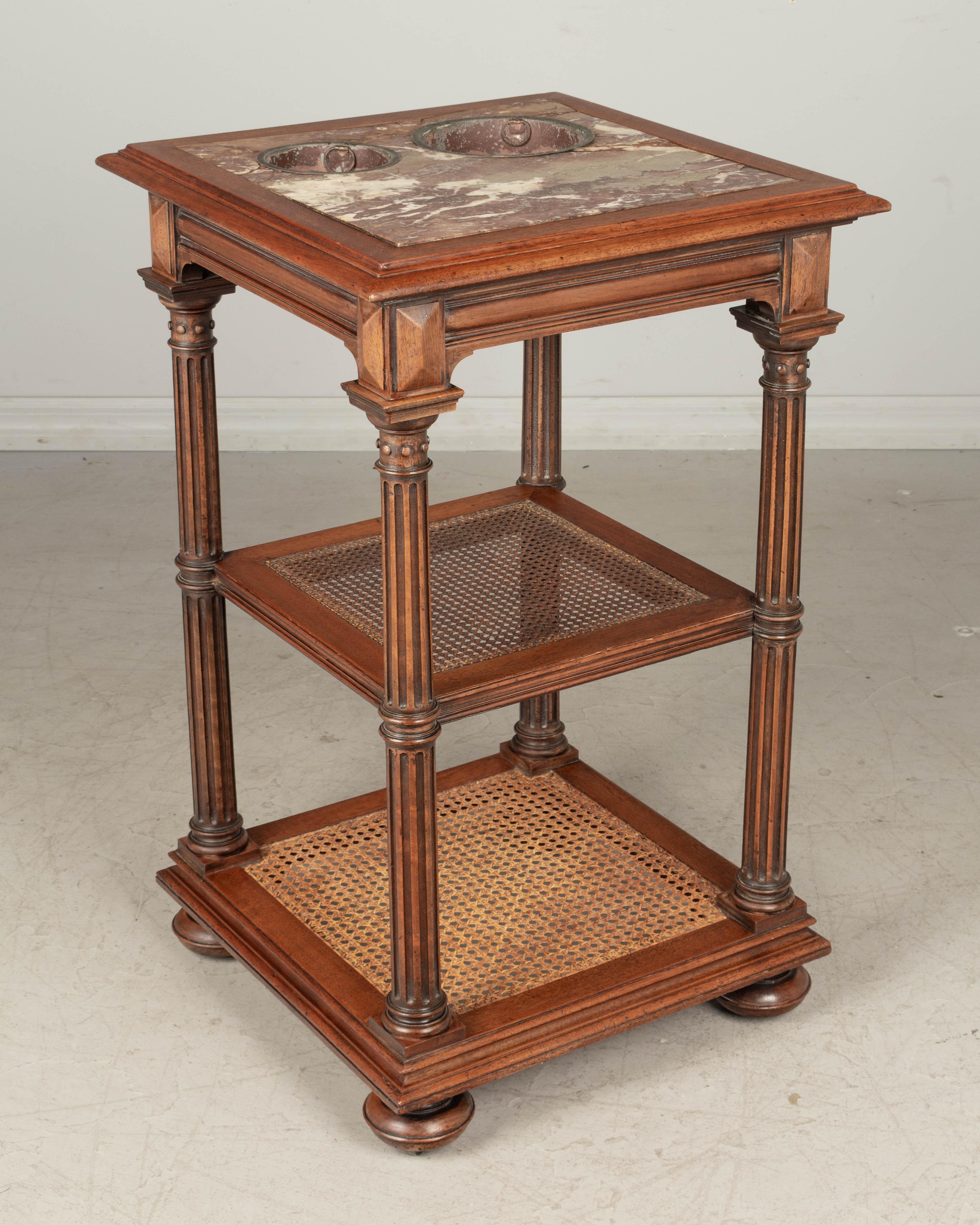 A 19th century Louis Philippe style French rafraichissoir, or side table with wine coolers, made of solid walnut with fluted turned legs and cane shelves. Red veined marble top has two wine bucket inserts. Marble top is repaired. Waxed patina. These