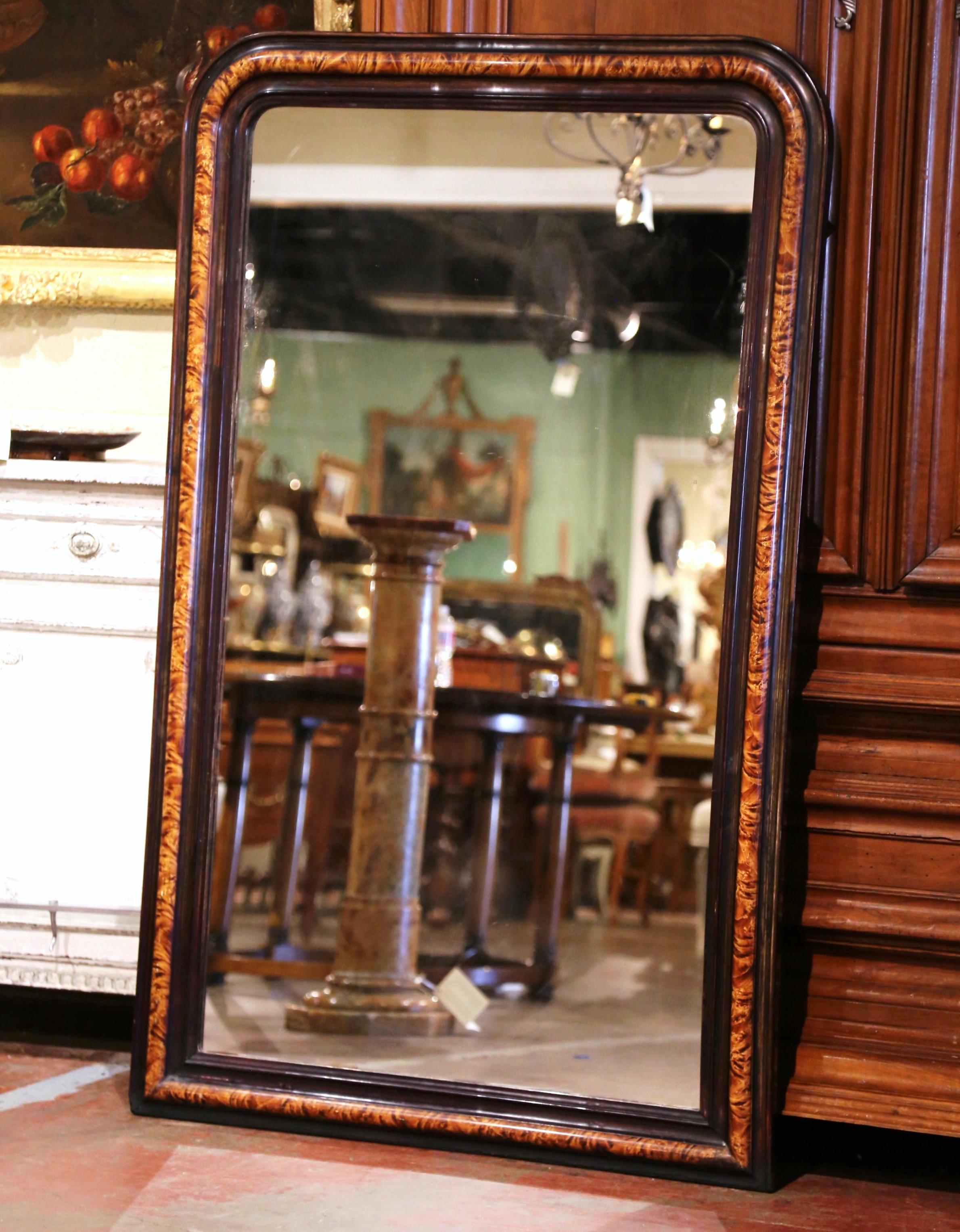 This elegant antique wall mirror was crafted in France, circa 1870. The tall frame is decorated with faux burl wood motifs in between patinated brown paint finish. The large two-tone mirror is in excellent condition with its original mercury glass