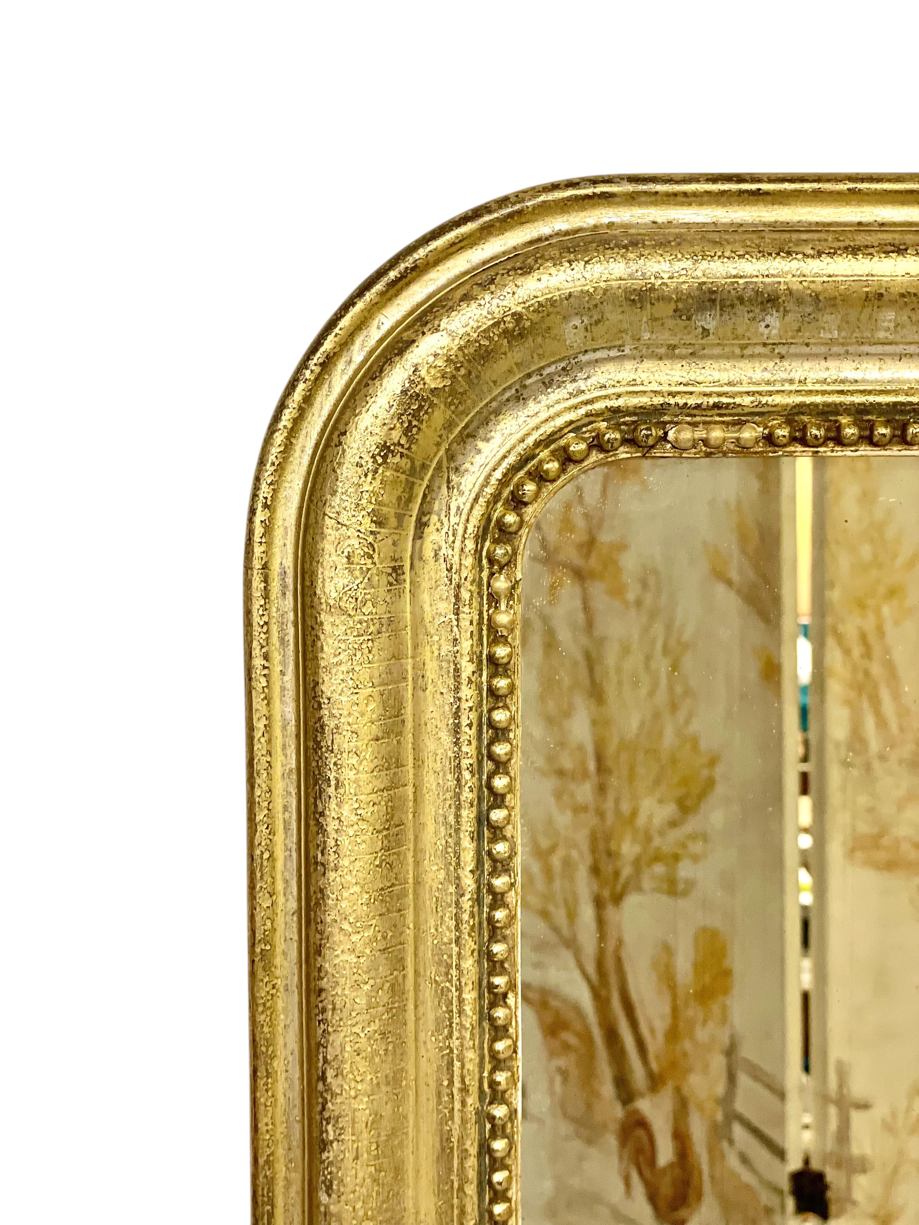 This elegant Louis-Philippe period mirror dates to the 19th century and is a fine example of French craftsmanship from the period. The frame features the classic rounded top typical of the Louis-Philippe style, and is made of carved wood with its