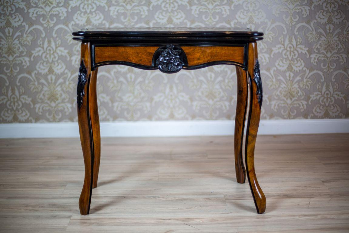 Wir präsentieren Ihnen einen Tisch aus Nussbaumholz, gemeinhin als Kartentisch bekannt, aus dem 3. Quartal des 19.
Dieses Möbelstück hat die Form eines Wandtisches auf gebogenen Beinen, mit einer klappbaren Platte mit gewellten Kanten, die von den