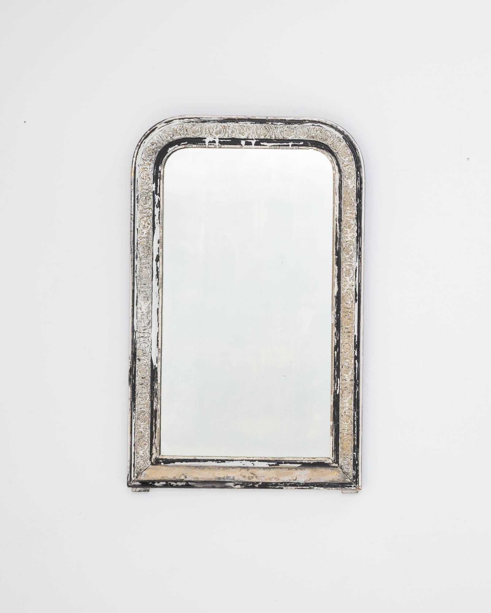 A wooden mirror created in 19th century France. Proudly aged, the off-white paint has worn to a gentle patina, unveiling auburn and amber hues that shine a noble contrast on the arched frame. This one of a kind mirror combines traditional design