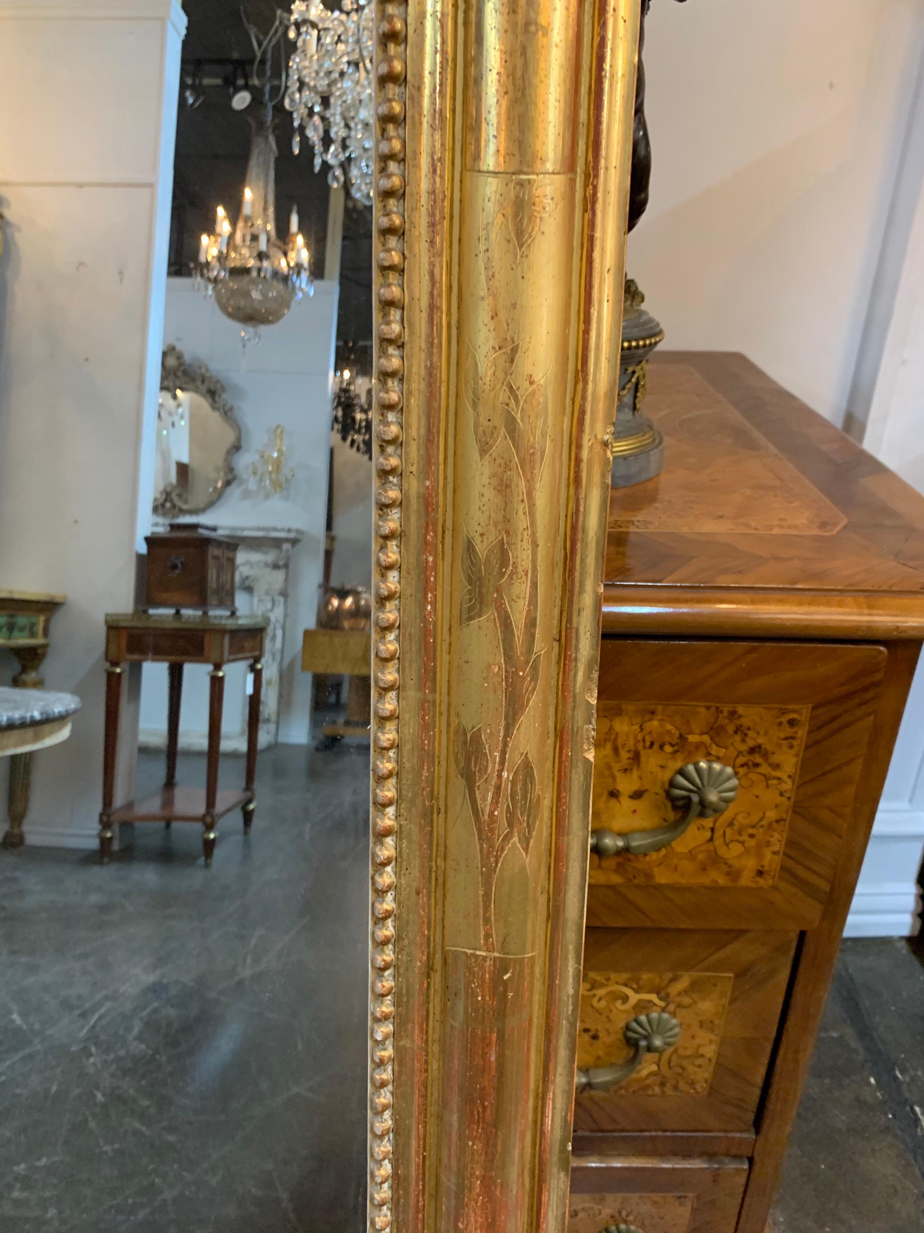 Beautiful 19th century gold gilt Louis Phillipe mirror. The mirror has reddish undertones, a beaded inside border and a floral design on the gilded area. A Classic design for a variety of decors!