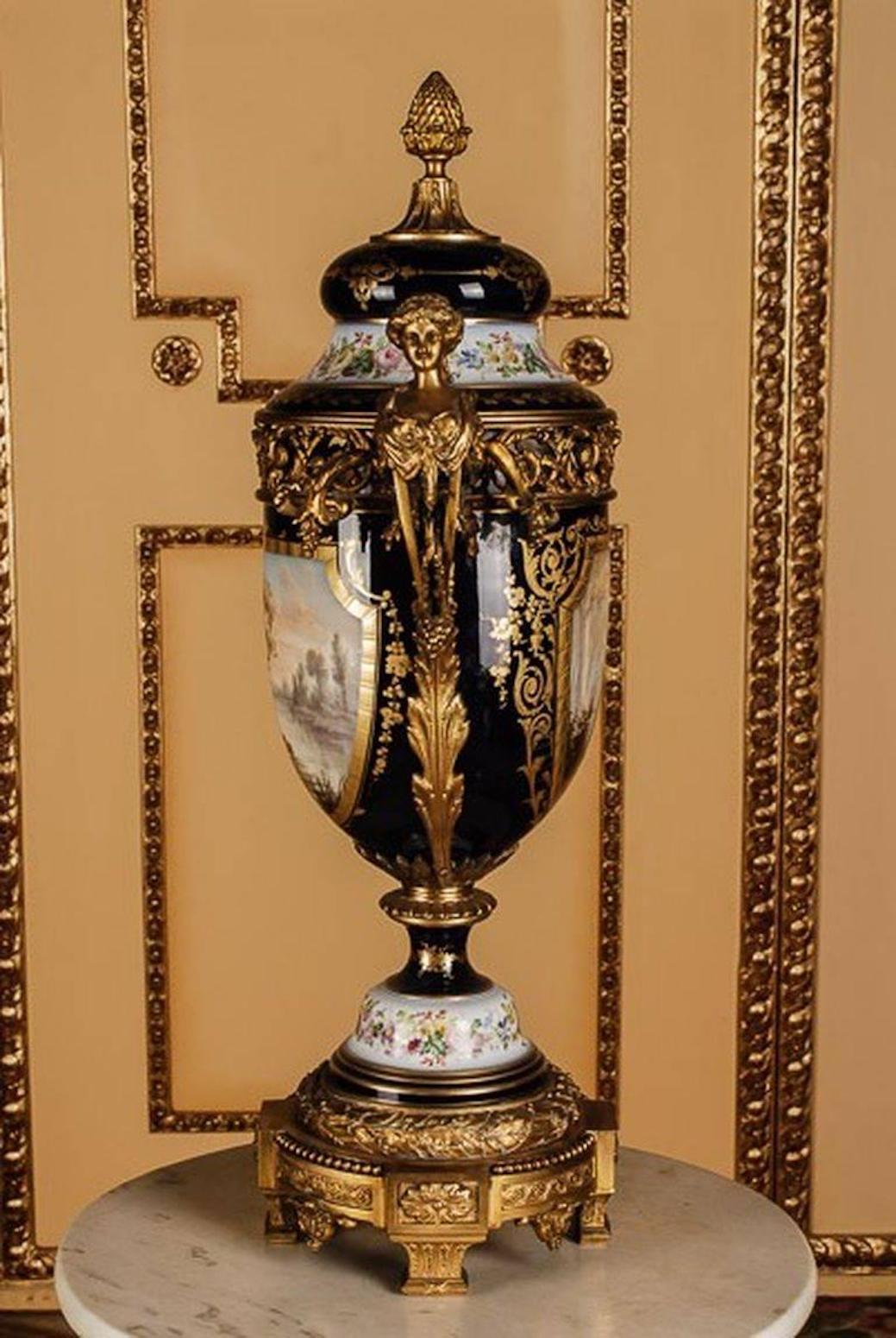 Gioielli di aspirazione in porcellana con rifiniture in bronzo dorato a fuoco estremamente fini e molto decorative. Sulle ombre, in uno sfondo blu cobalto, ricca cornice floreale ornamentale in oro. In alto riserve viola con raffigurazioni colorate