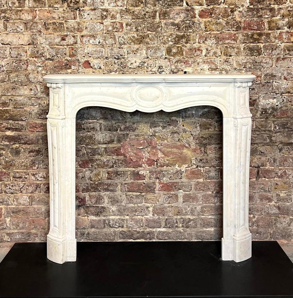 Cornice per caminetto in marmo bianco di Carrara Louis del XIX secolo. 
Questo caminetto antico in stile francese è caratterizzato da curve sensuali e asimmetrie, che riflettono lo stile rococò in contrasto con la simmetria del periodo barocco. Le