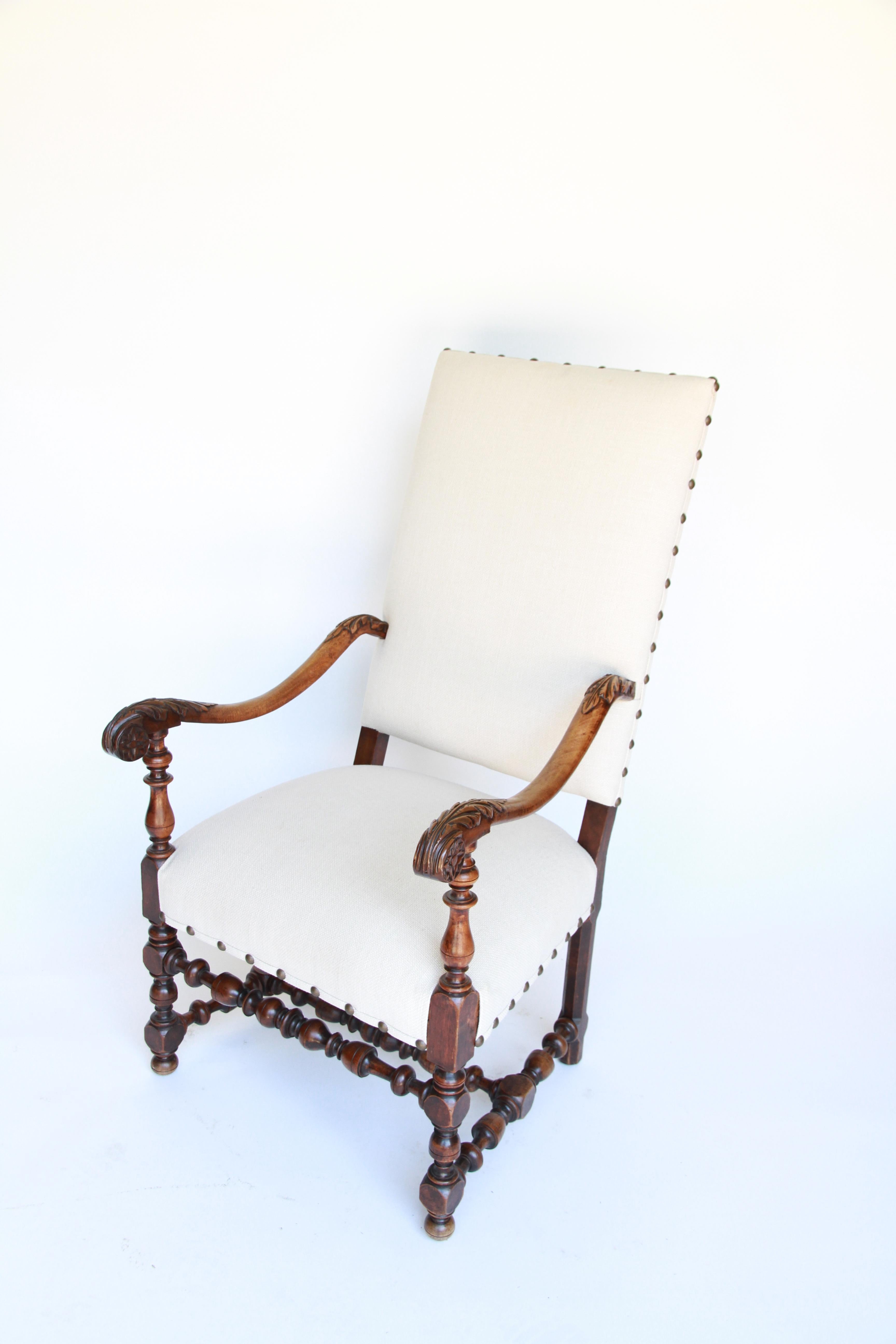 A 19th century French carved armchair. Each arm is beautifully carved with acanthus leaf detail, the legs and stretchers are turned wood. The chair is newly upholstered and has a nailhead trim.