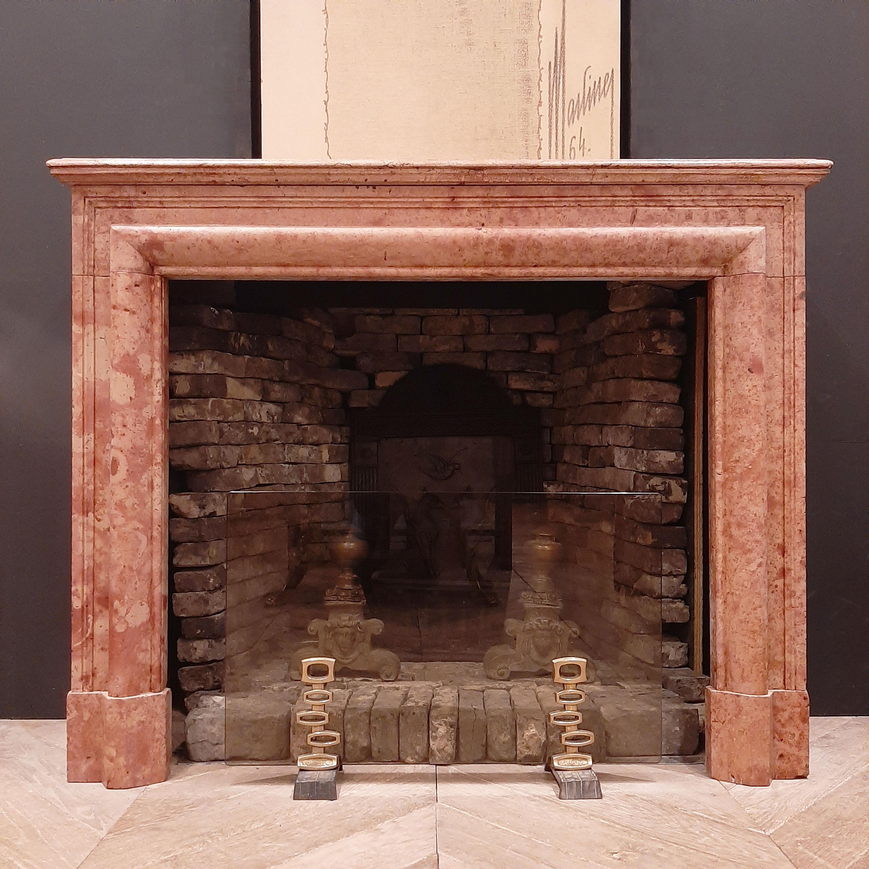 Antique French fireplace in Louis XIV style from the 19th century. This stunning mantelpiece in orange various marble has variety of warm colours, from beige/yellow to peachy pink. With its clean lines and its soft and swirly pattern in these