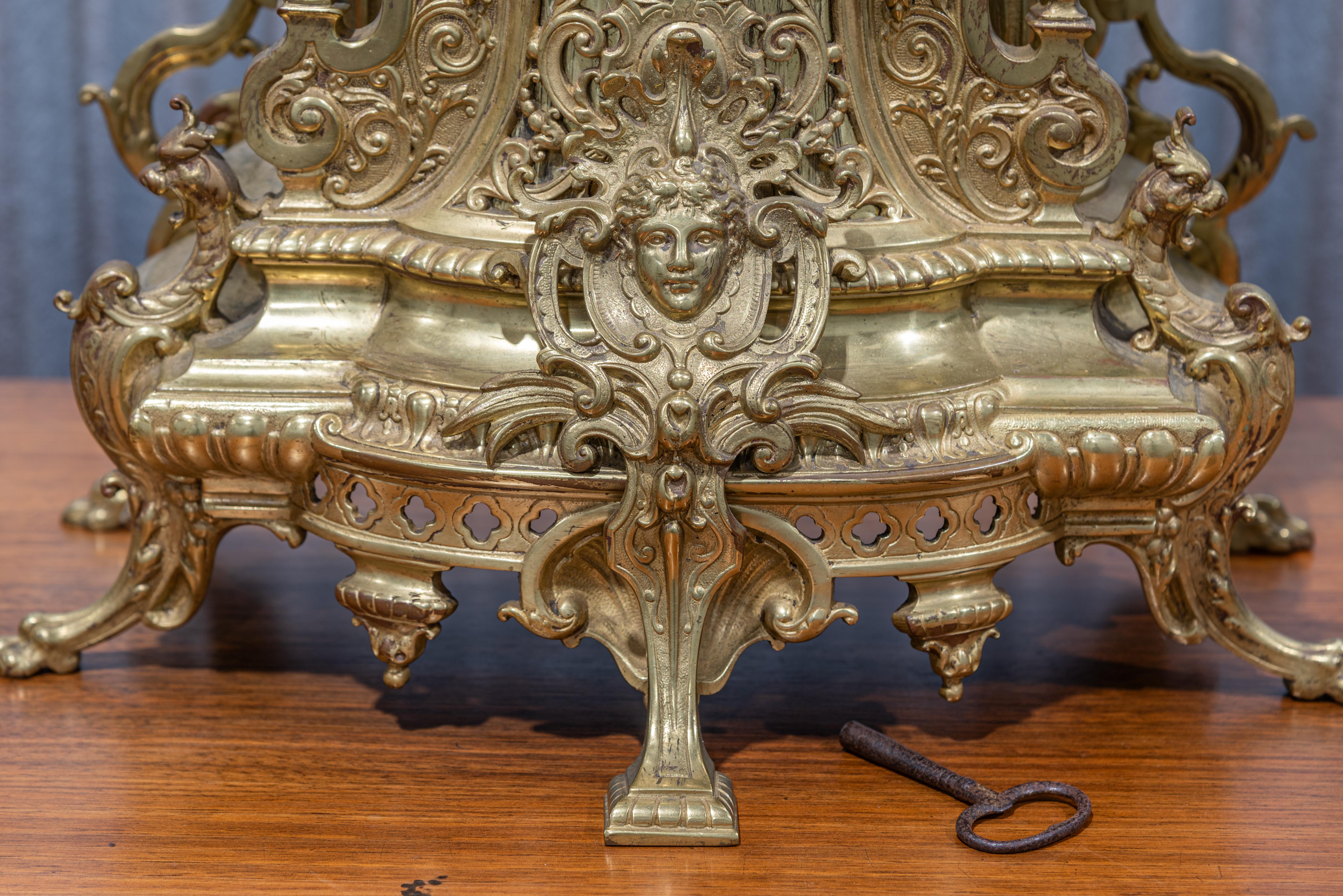 Transport yourself to the grandeur of 19th-century France with this exquisite Gilt Bronze Louis XIV Style Garniture De Cheminée. This garniture, or fireplace set, is a testament to the opulence and artistry of the era.

Crafted from gilt bronze,