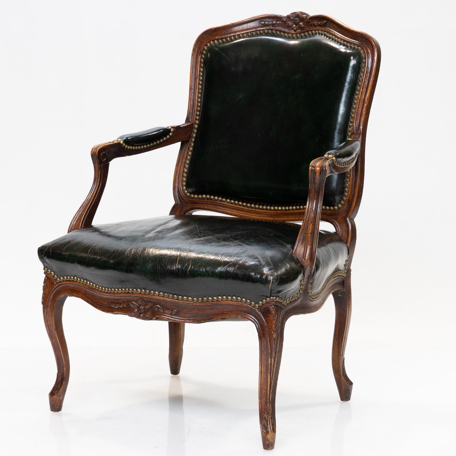 19th century Louis XV cabriolet armchair with a dark green leather covering. The cabriolet chair has a floret cresting back, floret on the seat rail, and a flower legs. Made of beechwood and has a wonderful patina. This cabriolet armchair is more of