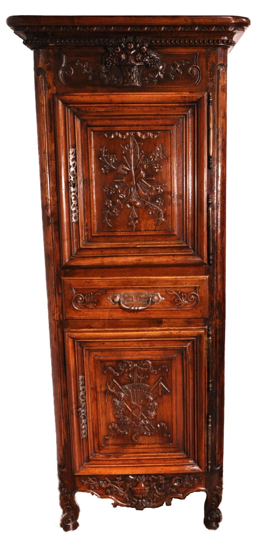 This elegant carved antique Homme-Debout was crafted in southern France, circa 1840. The fruitwood cabinet features two single carved doors above and below a center drawer. The exterior is tastefully hand carved with musical instruments, a flower