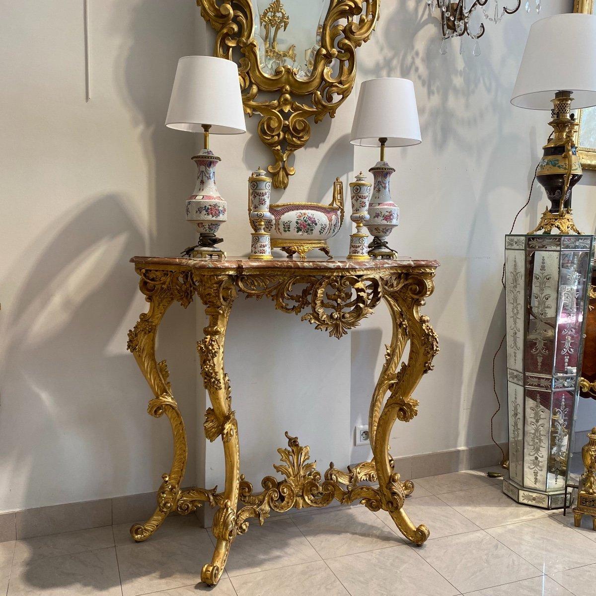 Wir präsentieren Ihnen diesen prächtigen Konsolentisch im Übergangsstil Louis XV aus der Zeit Napoleons III. Er ist aus vergoldetem Holz und wird von vier durch eine Bahre verbundenen Cabriole-Beinen getragen. Seine elegante Erscheinung wird durch