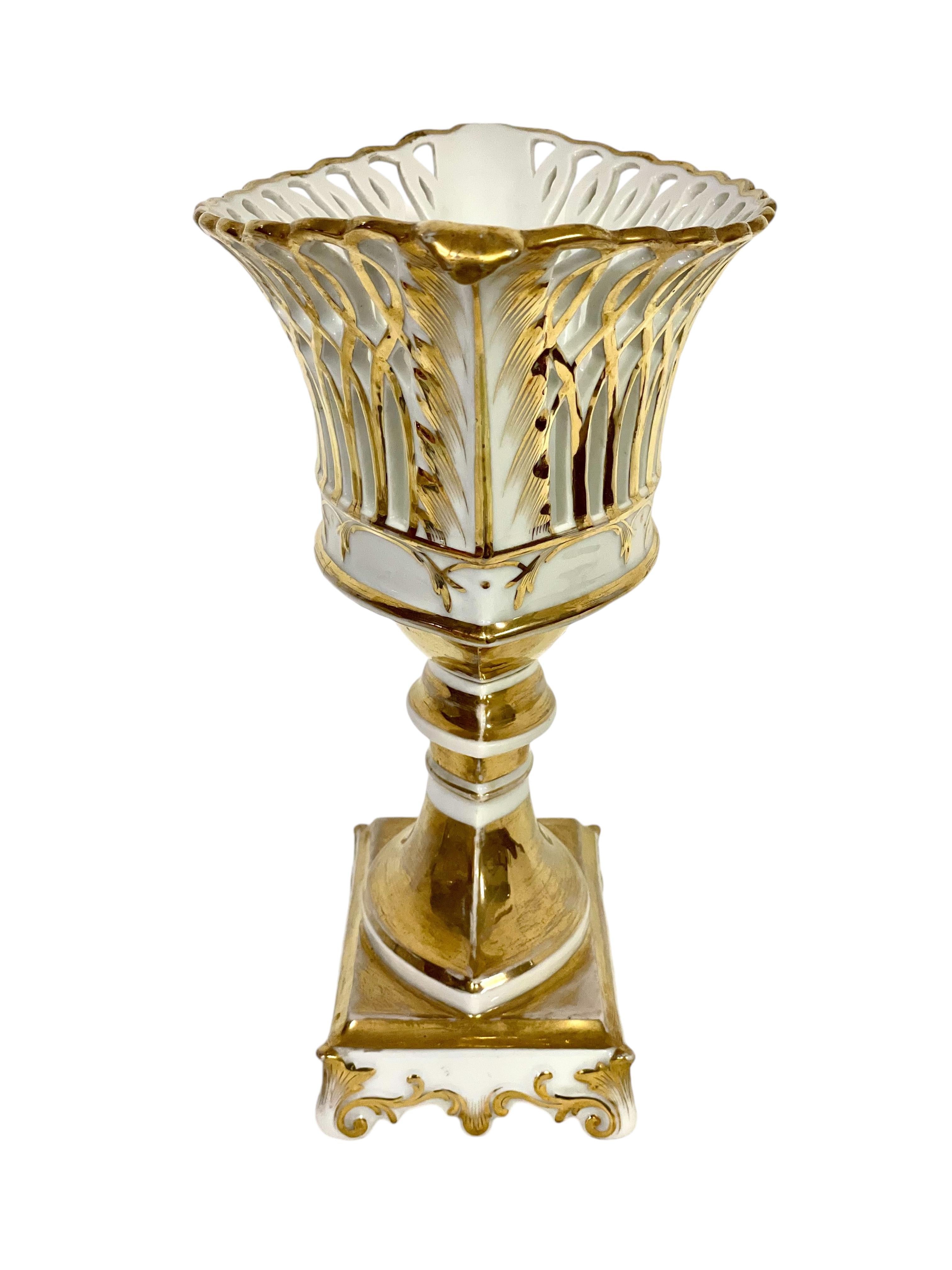 An elegant old Paris porcelain reticulated compote, or fruit basket, crafted in the Louis XV style, and raised on an ornately decorated pedestal and square base. This oval basket, with its fine, openwork sides, is generously embellished with gilt