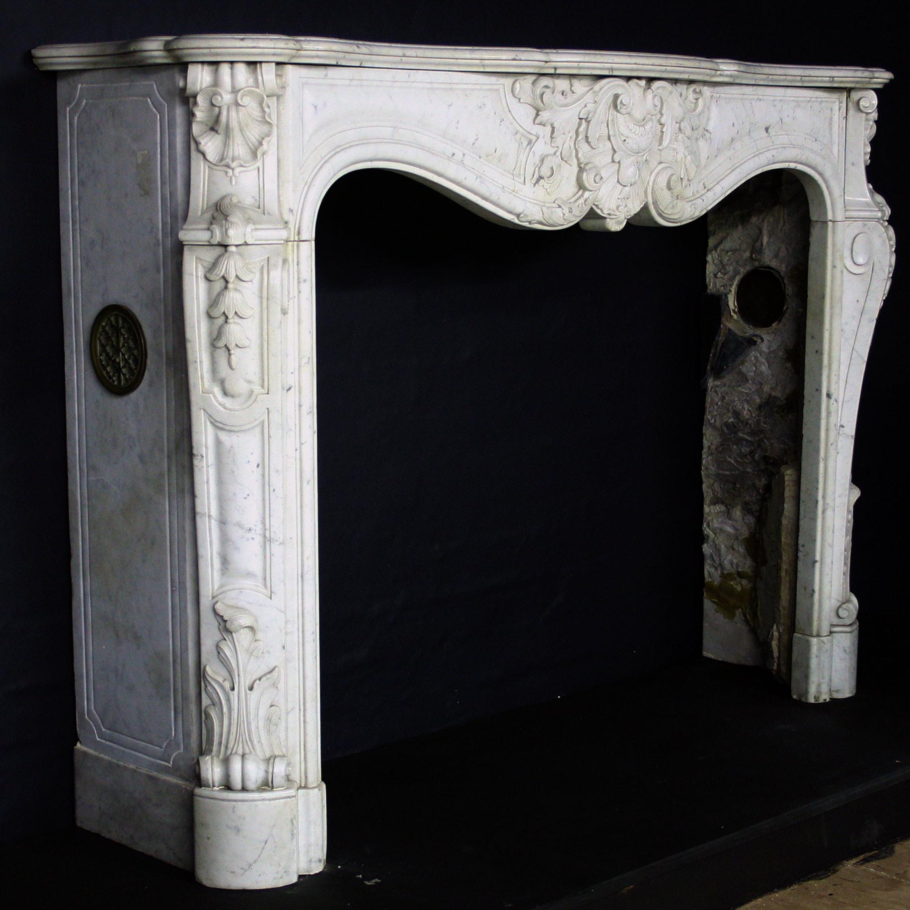 An elegant Sicilian marble Chimneypiece in the Louis XV style. Below an arc-en-arbolette shelf, the serpentine frieze has an elaborate shell cartouche with scrolling acanthus between raised and fielded panels. The Jambs comprise bold shell corner