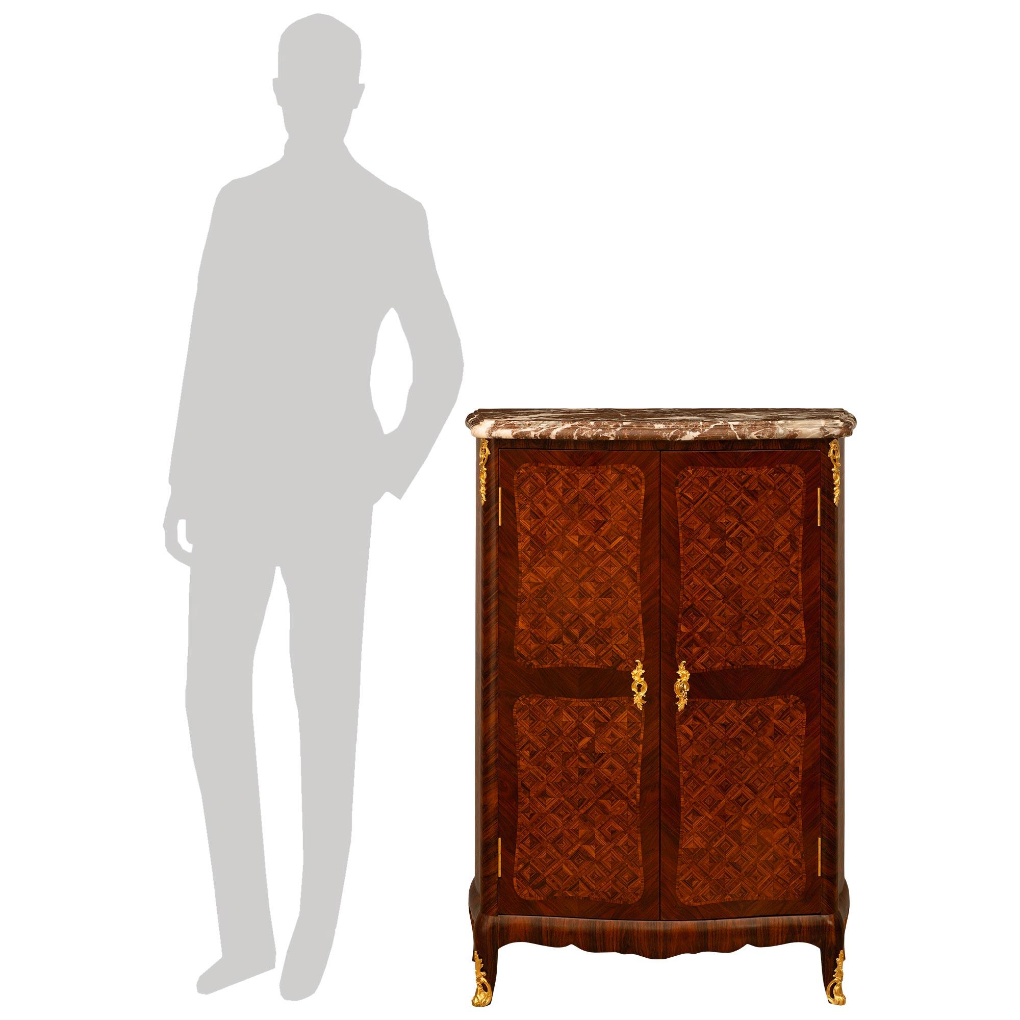 A stunning and wonderfully decorative pair of French late 19th century Louis XV st. Kingwood and Rouge Royal marble cabinets. Each his and hers cabinet with its original hardware is raised on four small scale cabriole legs. The two front legs are