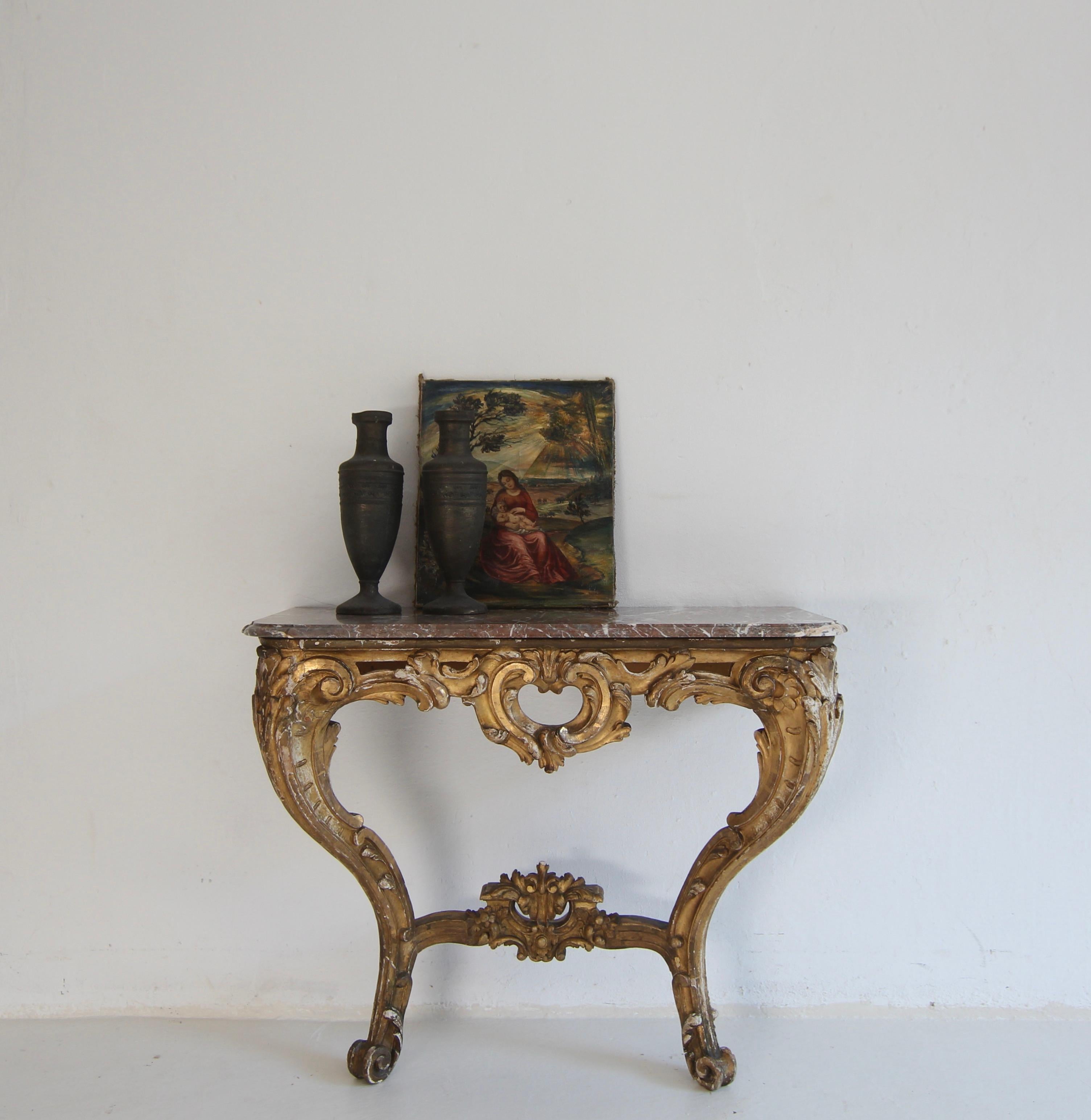 A 19th century Louis XV style wall console table with marble top. Probably from the Napoleon III epoch.

Gesso and gold painted, openwork carved and rocaille-shaped wooden frame, carved with leaves and flowers, with volute supports connected by