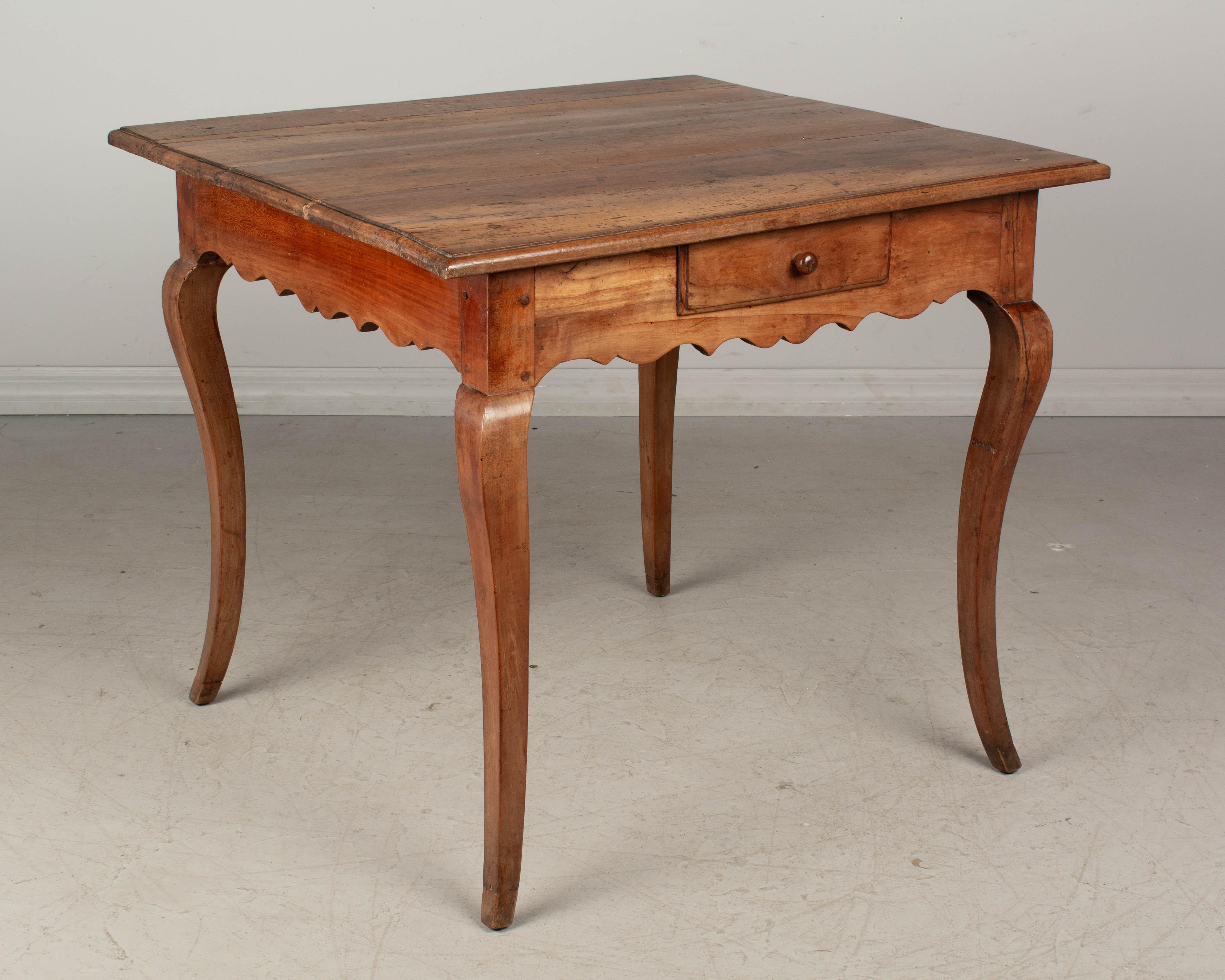 An early 19th century Louis XV style Country French side table with a cherry wood base and a walnut top. Two dovetailed drawers, scalloped apron and curved legs. Repairs on legs. Waxed Patina.
Please refer to photos for more details. Pictures are