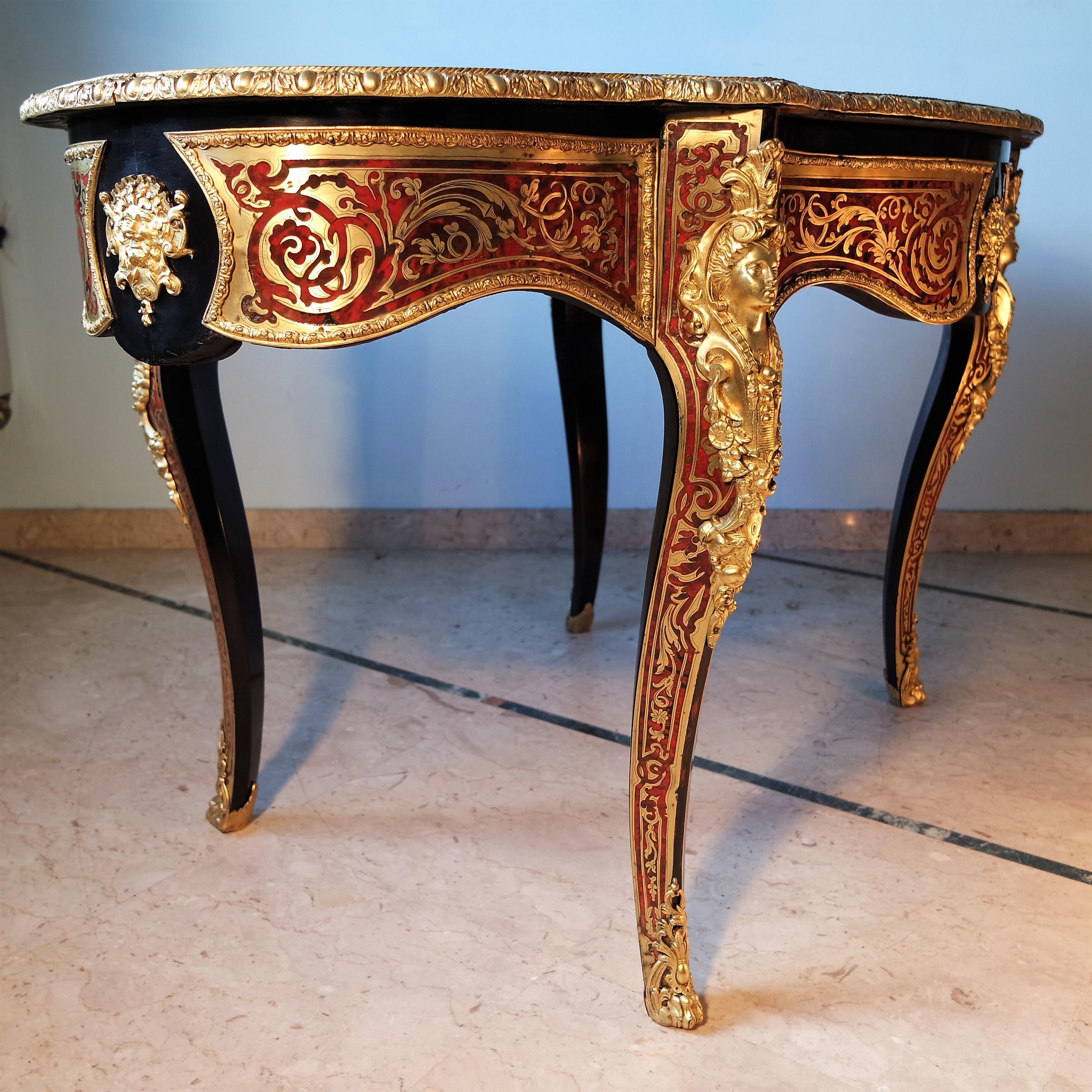 A rare and elegant Boulle style Bureau Plat inlaid with red tortoise and brass, engraved with arabesque motifs.
It is supported by four cabriolé rocaille legs.
In the belt, it has a drawer with a key.
Rich ornamentation of gilded bronzes and