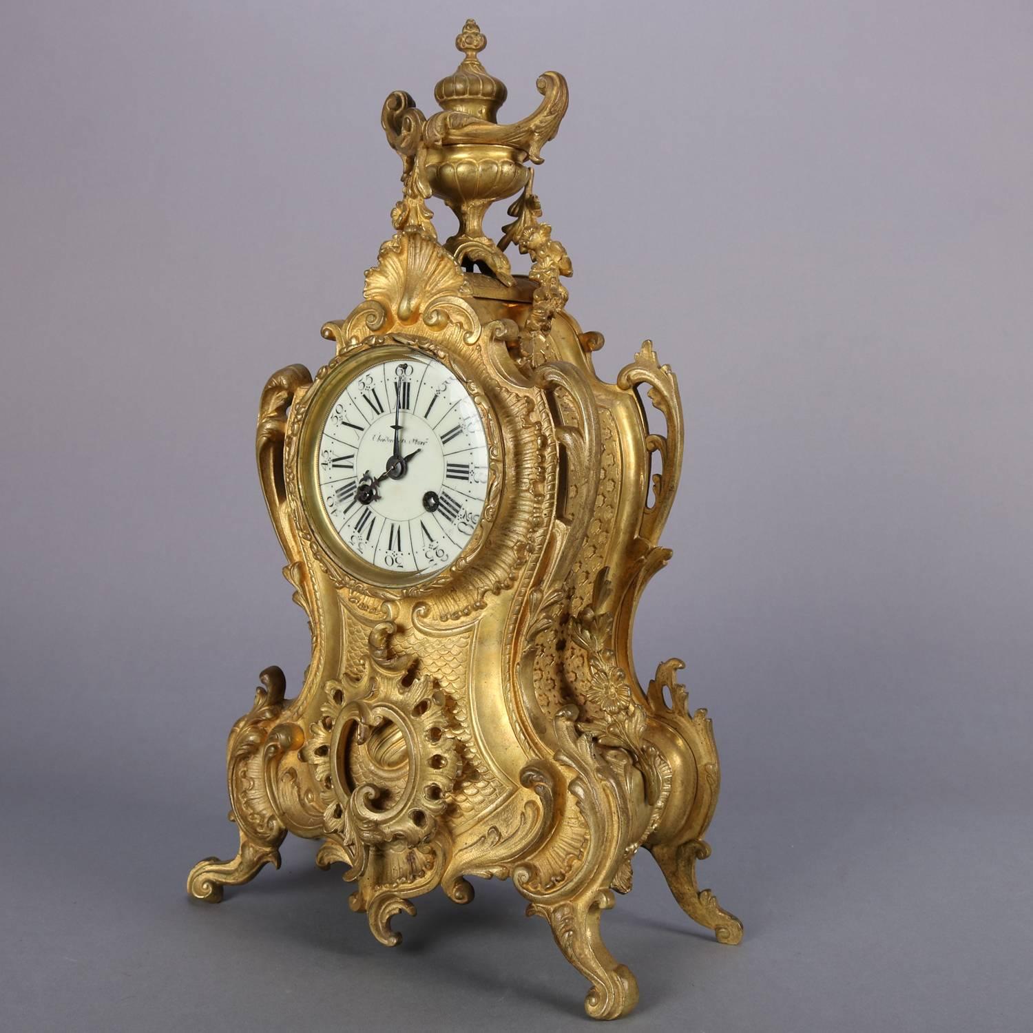 Antique Louis XV French Brevete mantel clock features gilt bronze case highly decorated with foliate and scrollwork with shell crest and urn finial atop scrolled feet, enamel face, movement stamped 